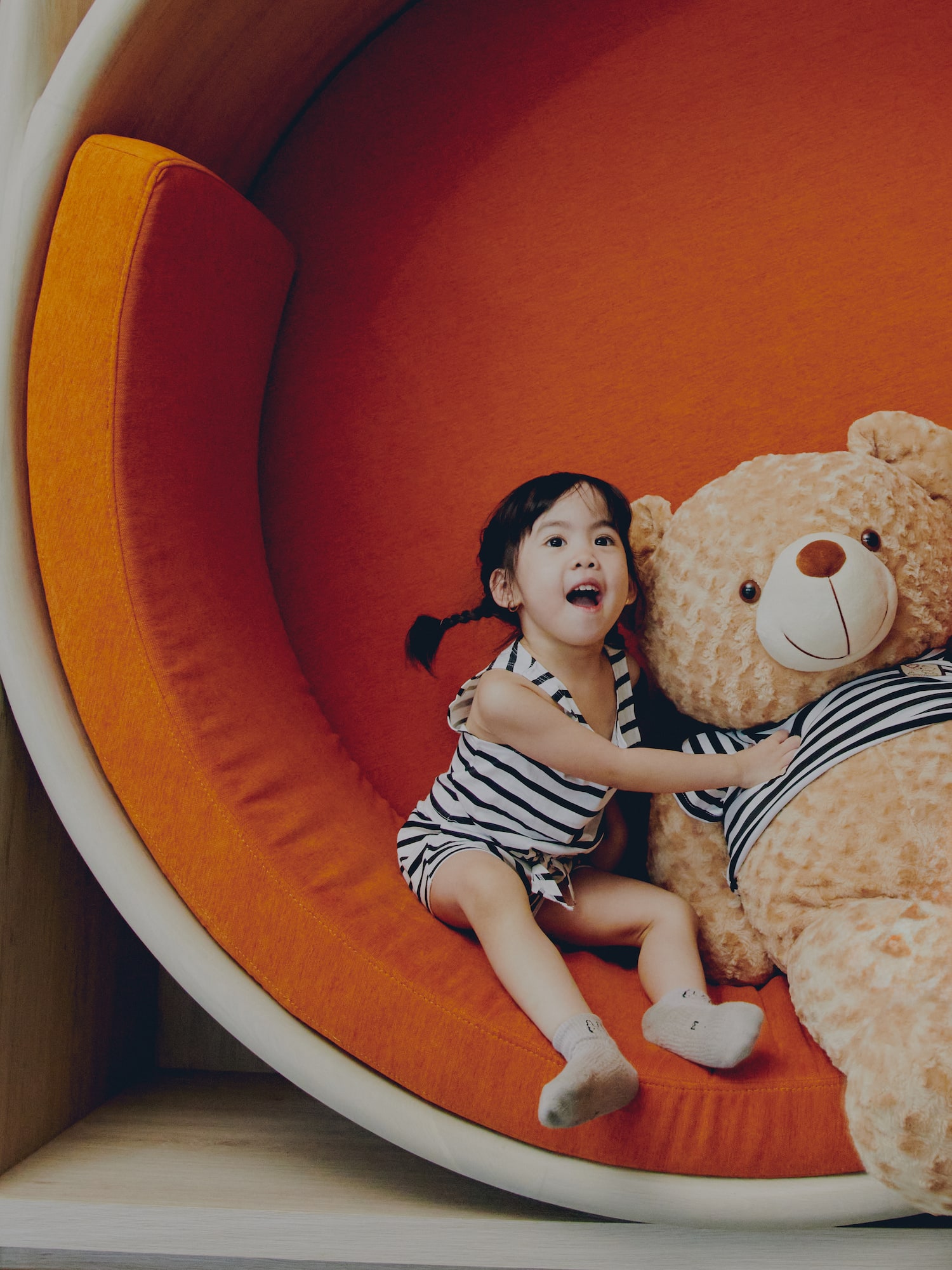 a girl sitting on a large stuffed bear