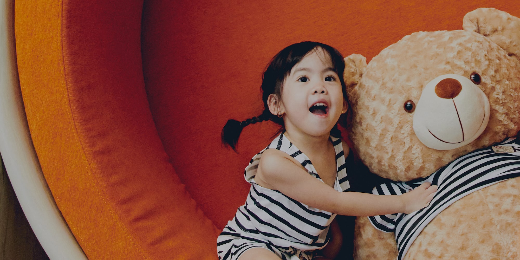 a girl sitting on a large stuffed bear