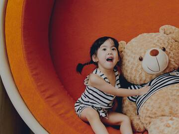 a girl sitting on a large stuffed bear