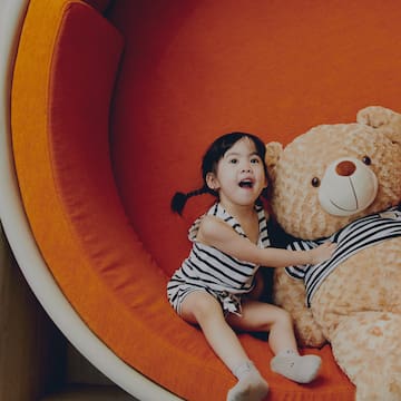 a girl sitting on a large stuffed bear