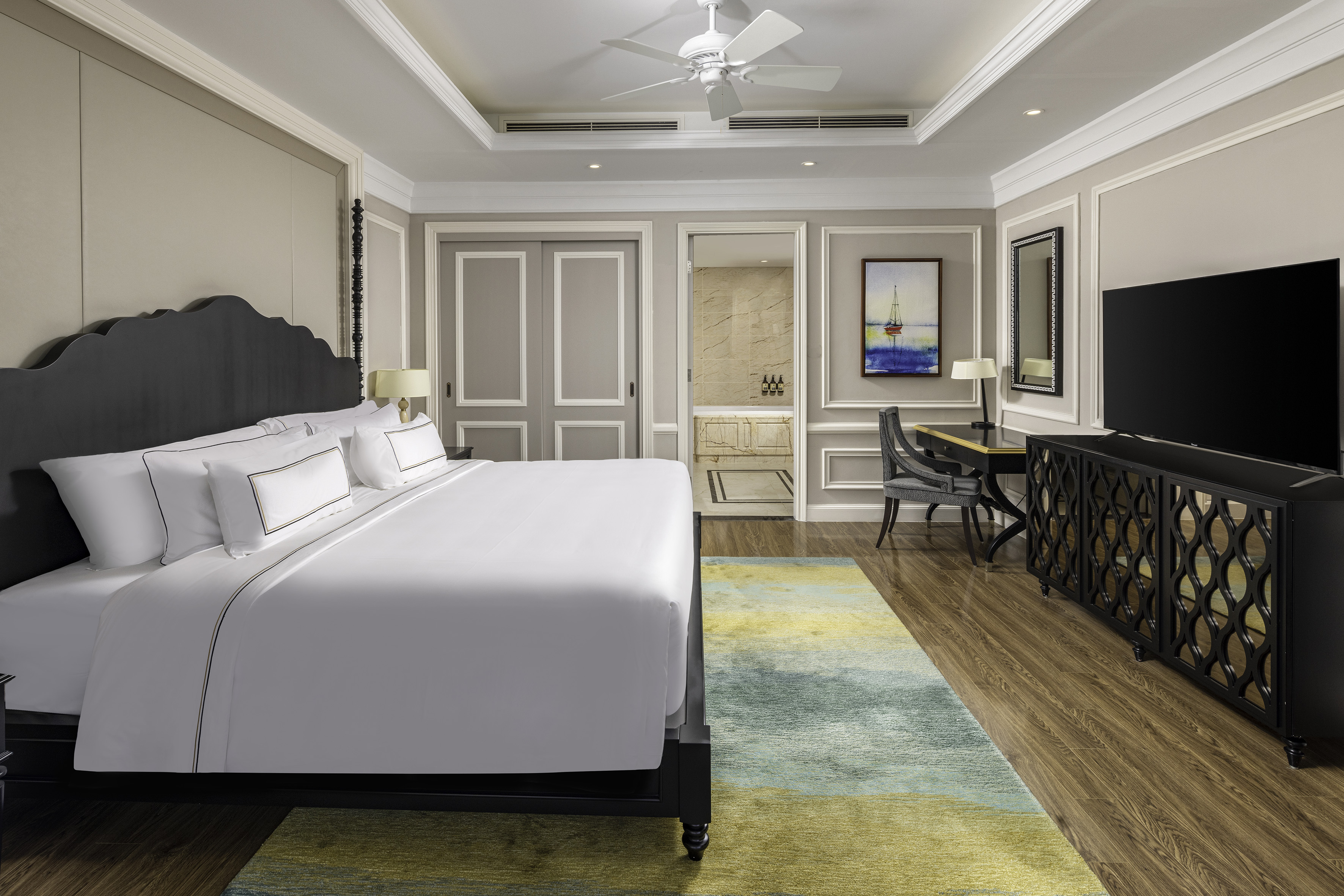 Luxury hotel bedroom with king bed, TV, desk, and bathroom access.