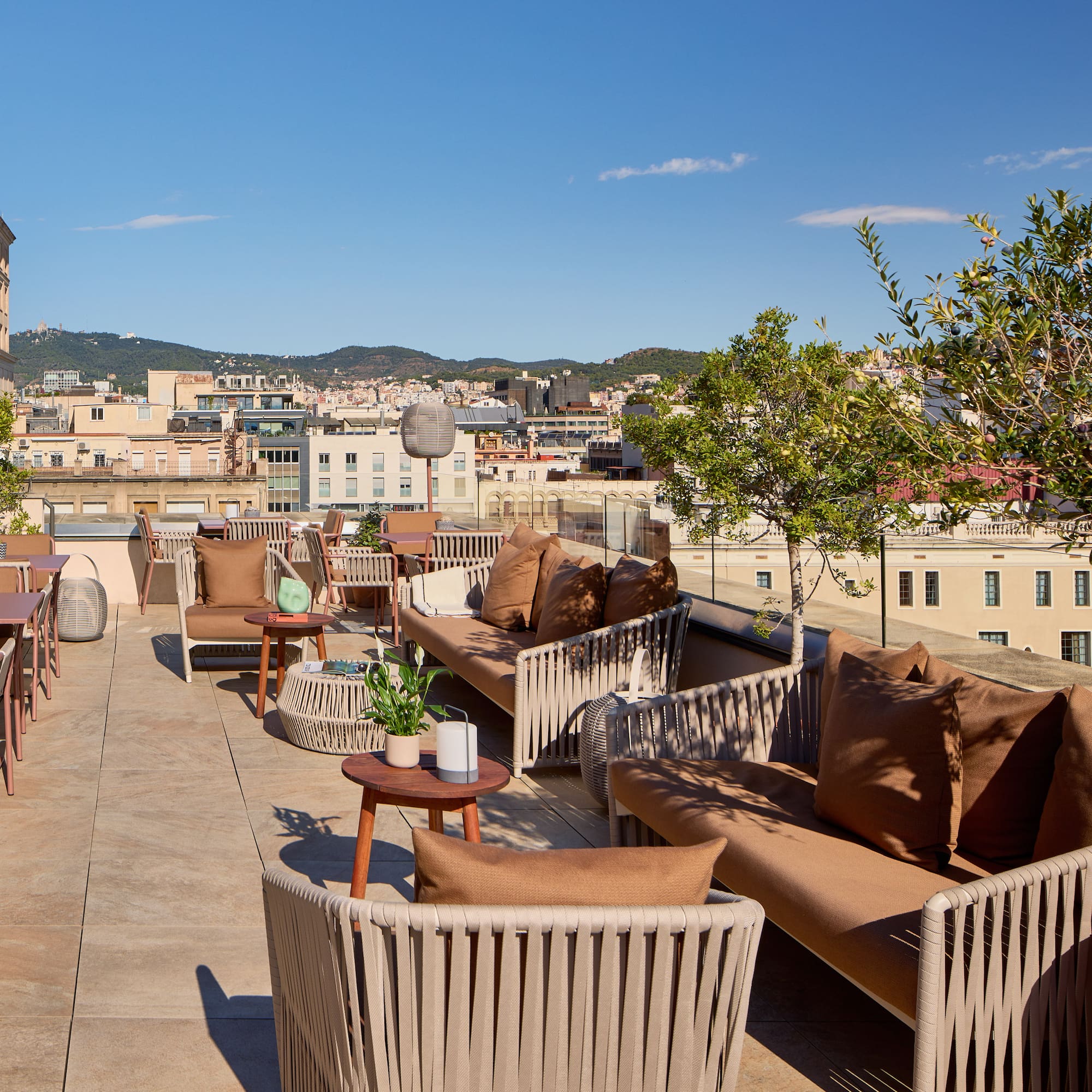 Hotel rooftop terrace with stylish outdoor seating and panoramic city views.