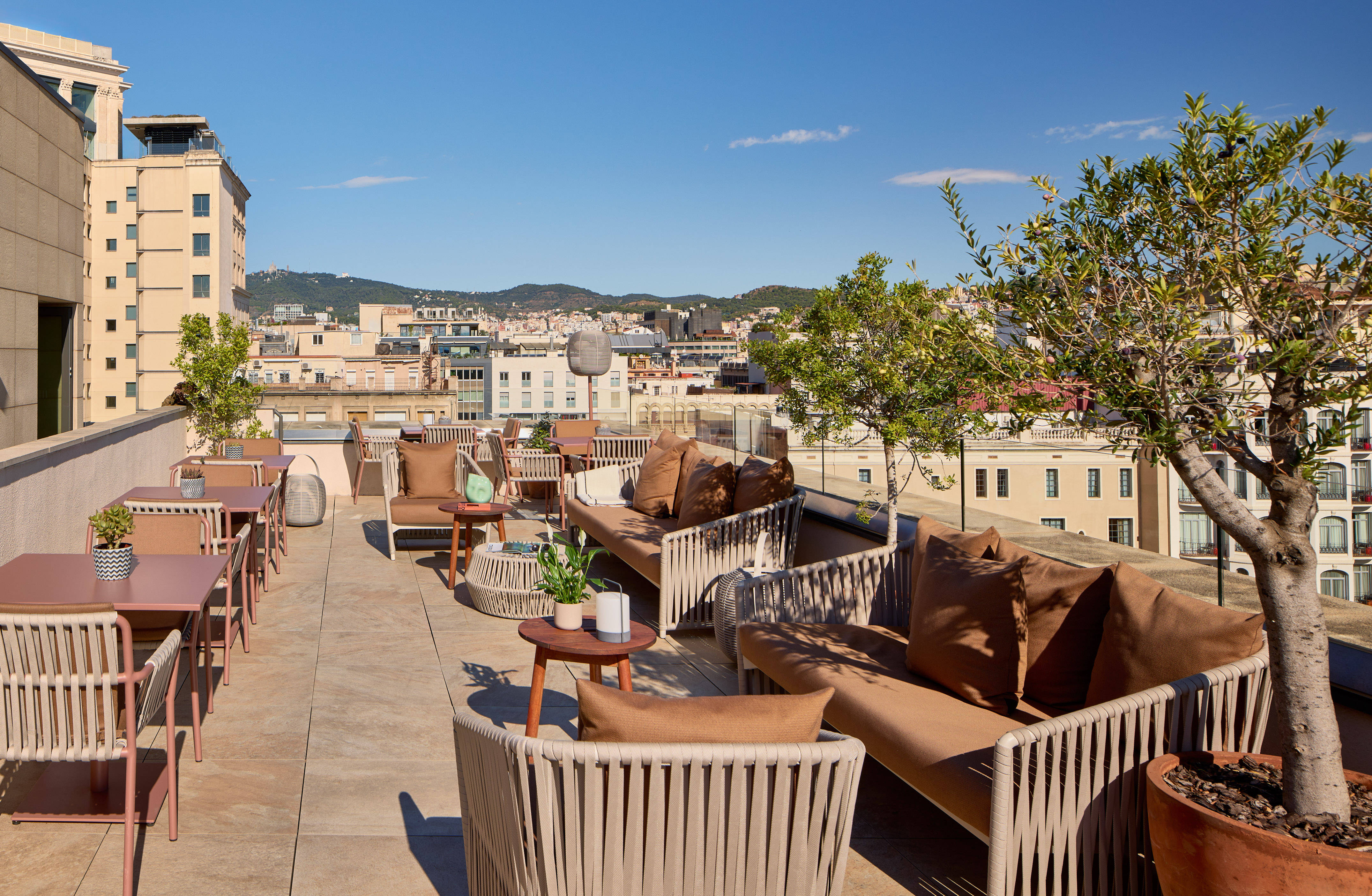 Hotel rooftop terrace with stylish outdoor seating and panoramic city views.