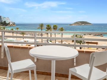 a table and chairs on a balcony overlooking a beach