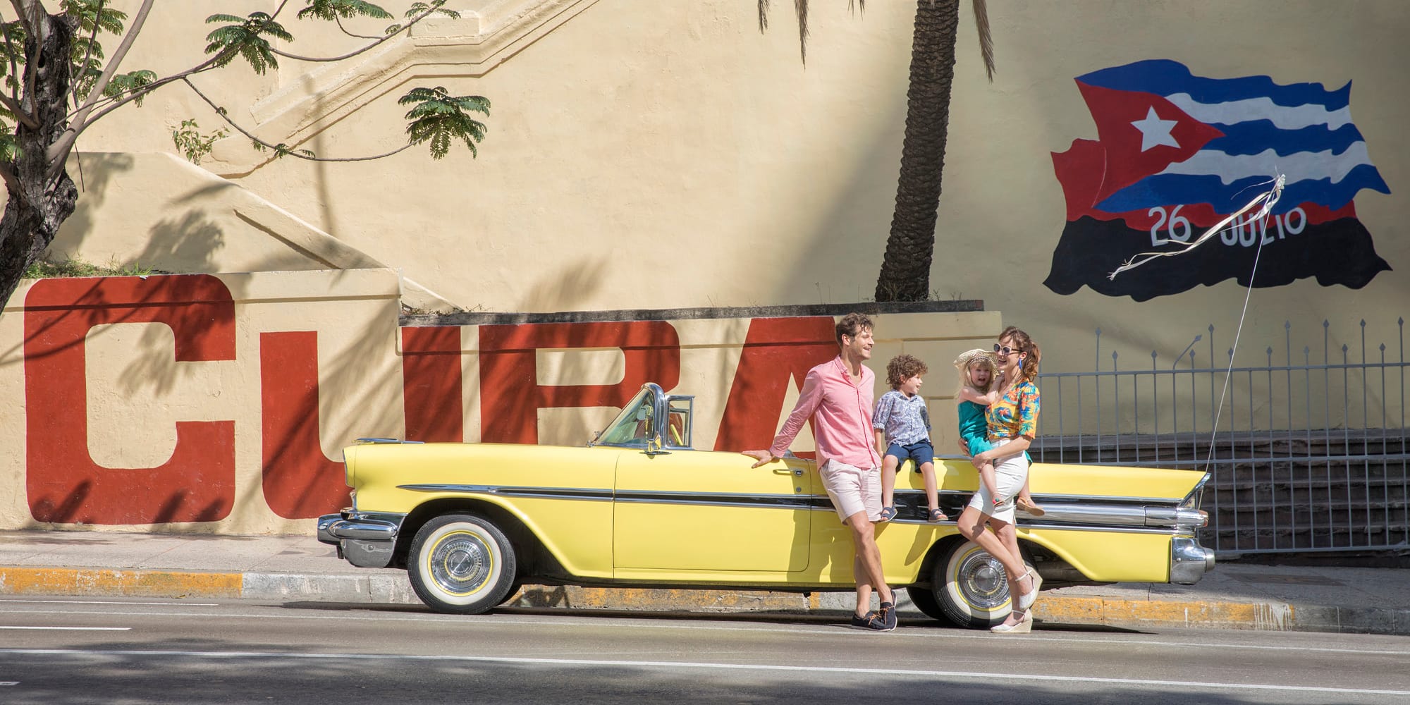 a family standing on a yellow convertible car