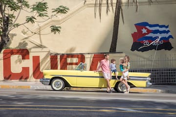 a family standing on a yellow convertible car