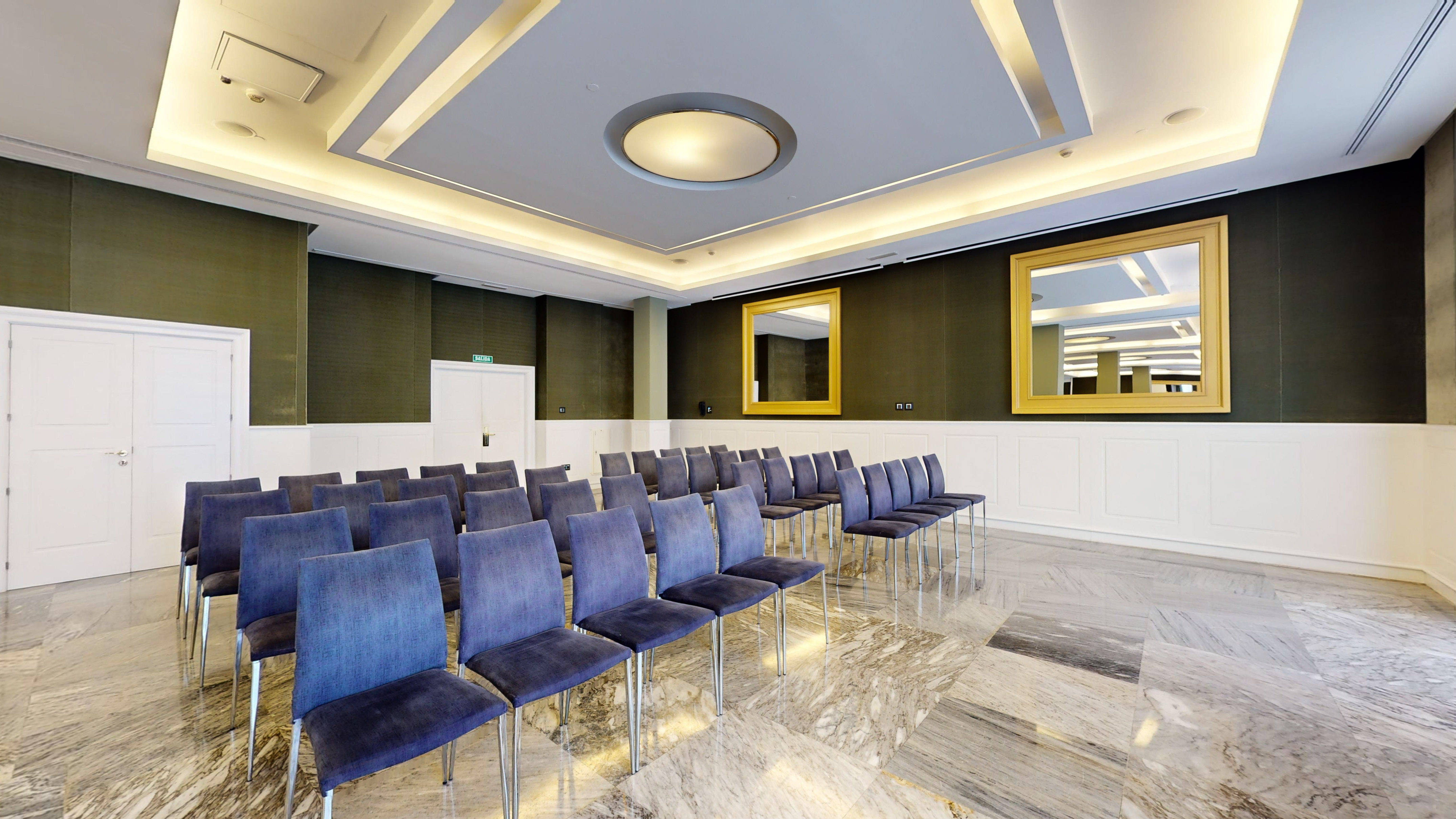 Modern meeting room with blue chairs, marble floor, and wall mirrors.