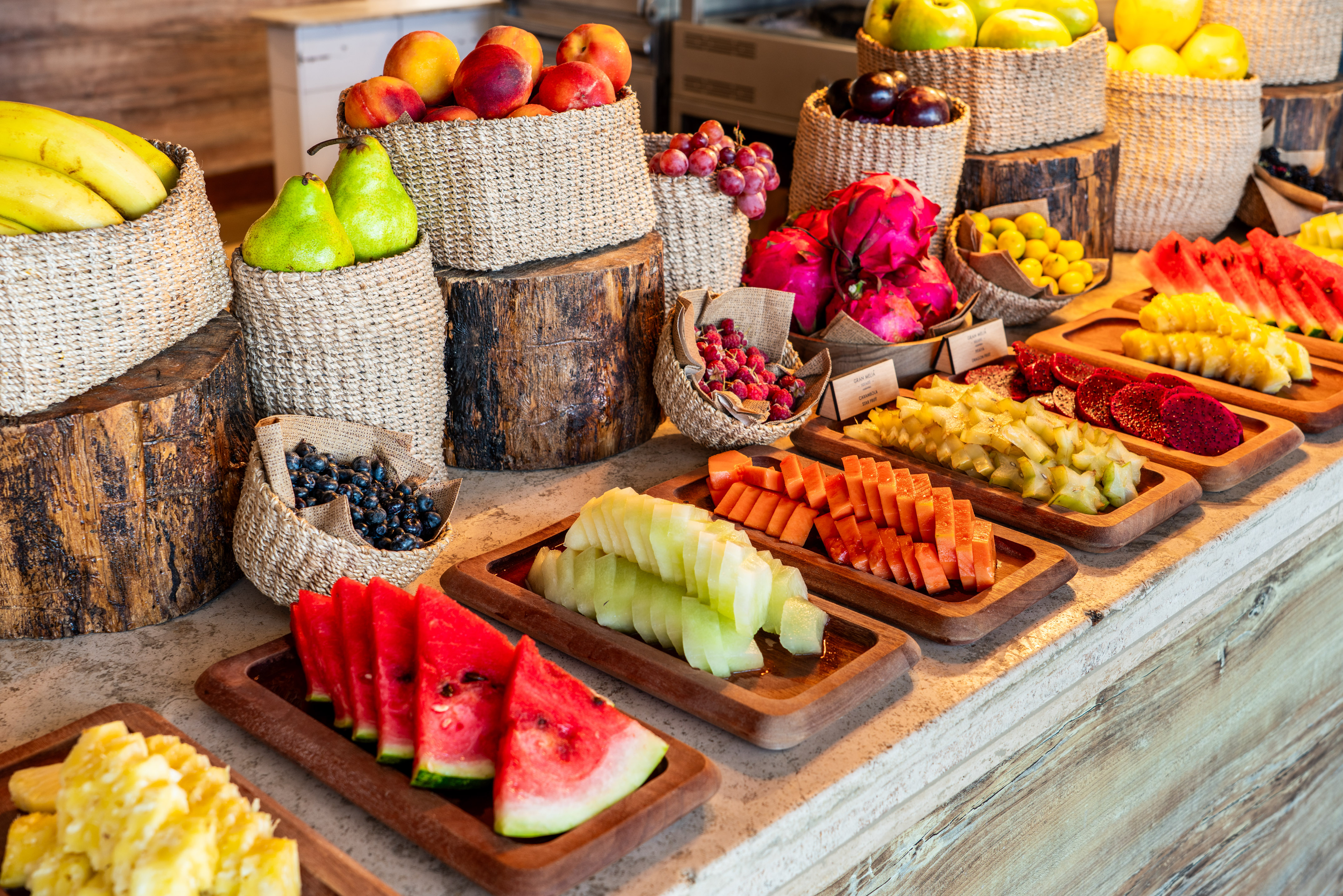 Fresh fruit buffet with sliced tropical and whole fruits.