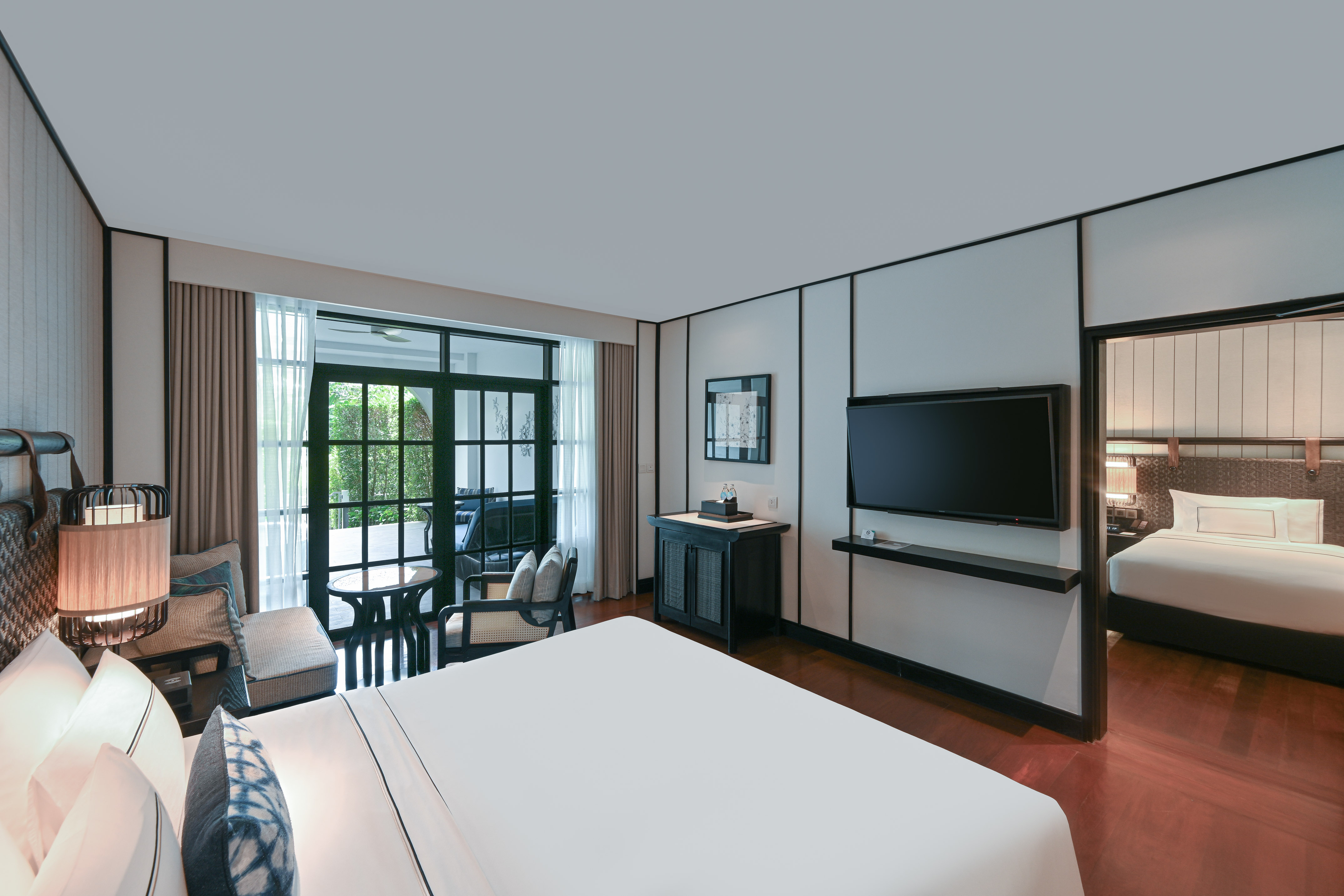 Luxury hotel suite with king bed, TV, private balcony, and adjoining room.