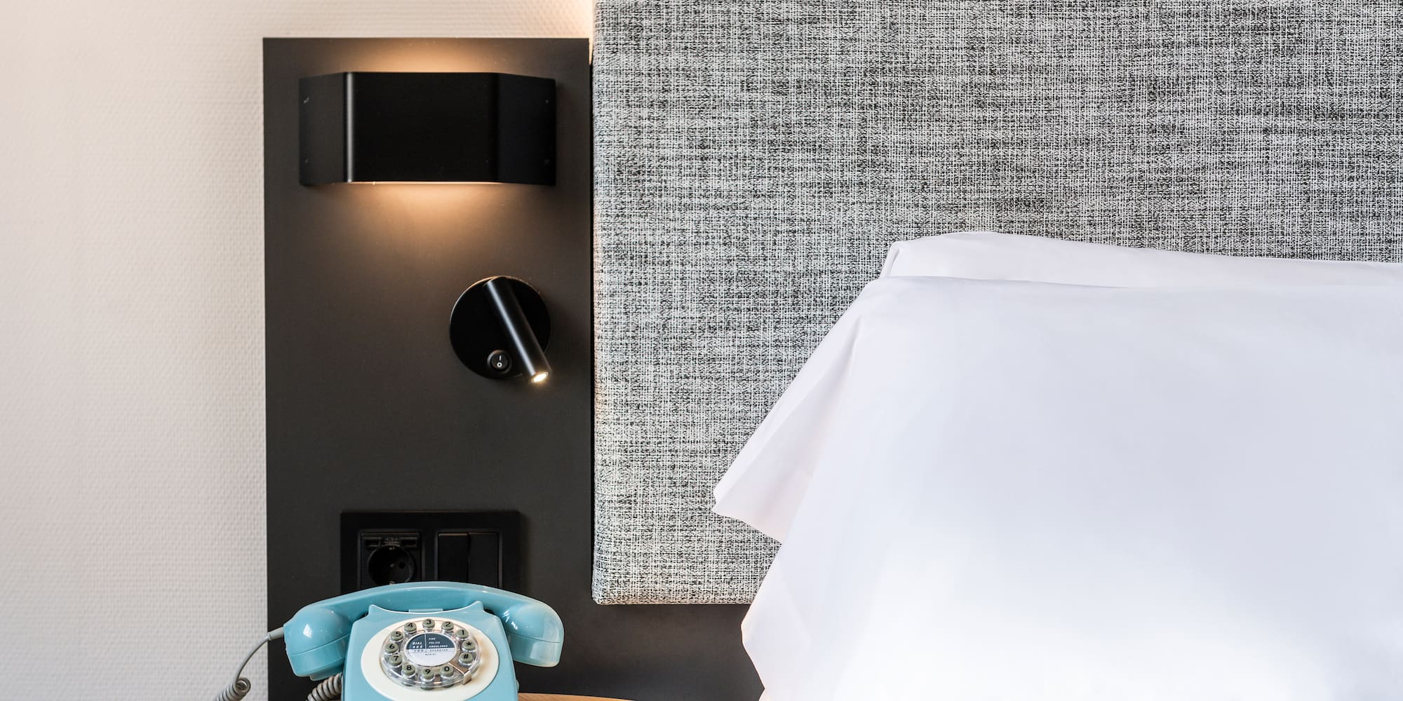 a telephone on a table next to a bed