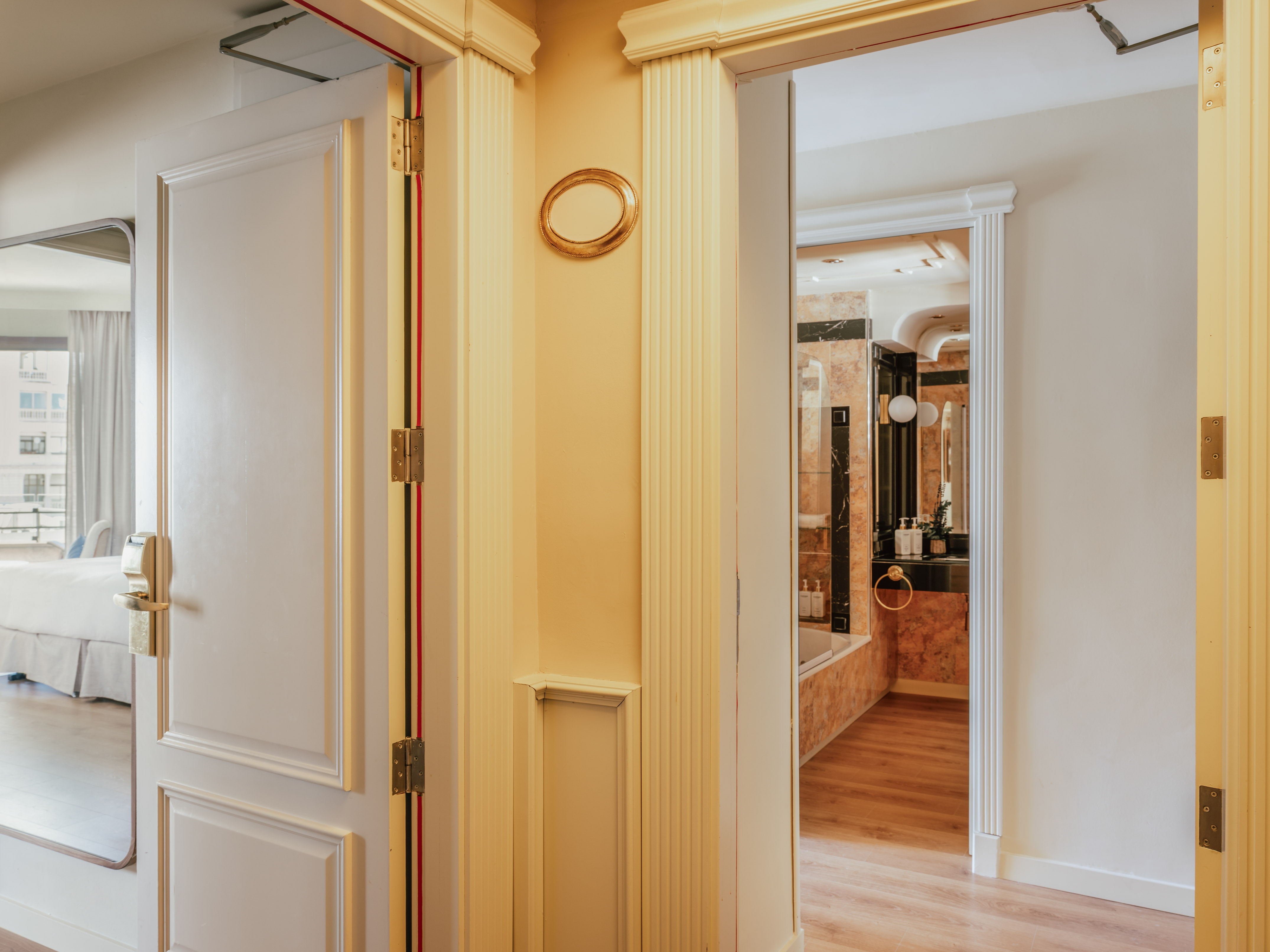 Open doors to a luxurious hotel suite bedroom and marble bathroom.