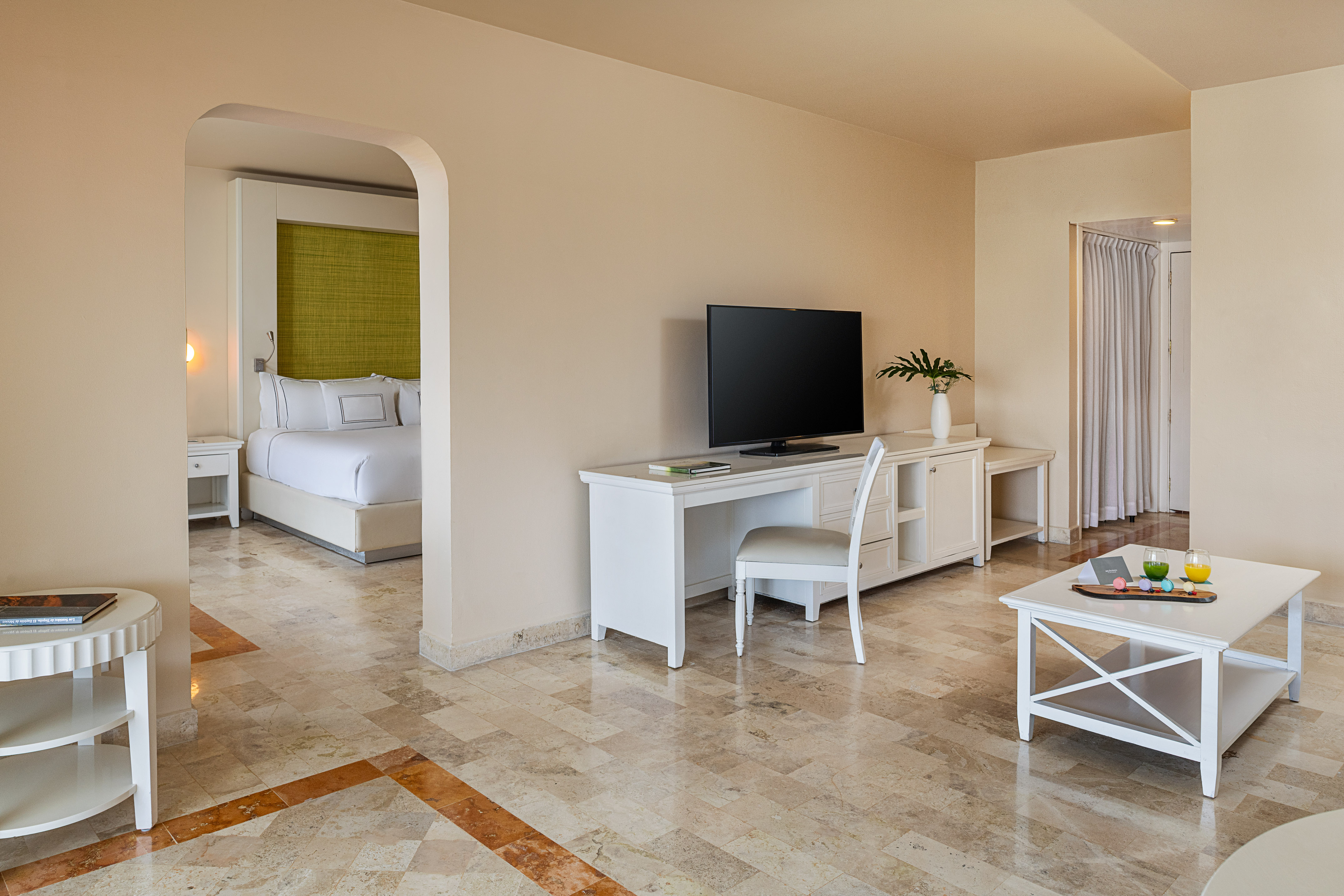 Bright hotel suite with living room, bedroom, TV, and modern tile floor.