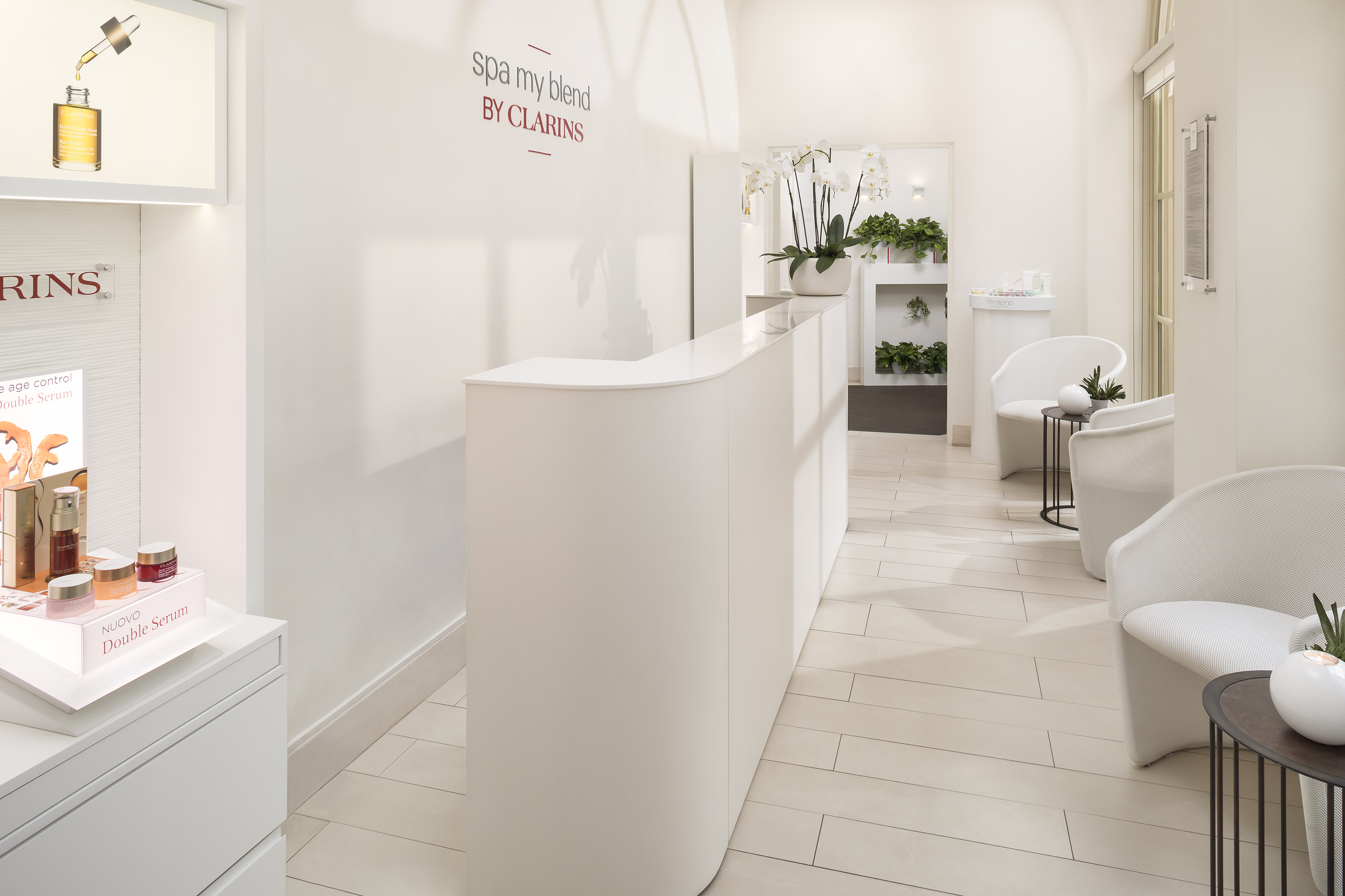 Clarins spa reception with white desk, elegant waiting area, and skincare products.