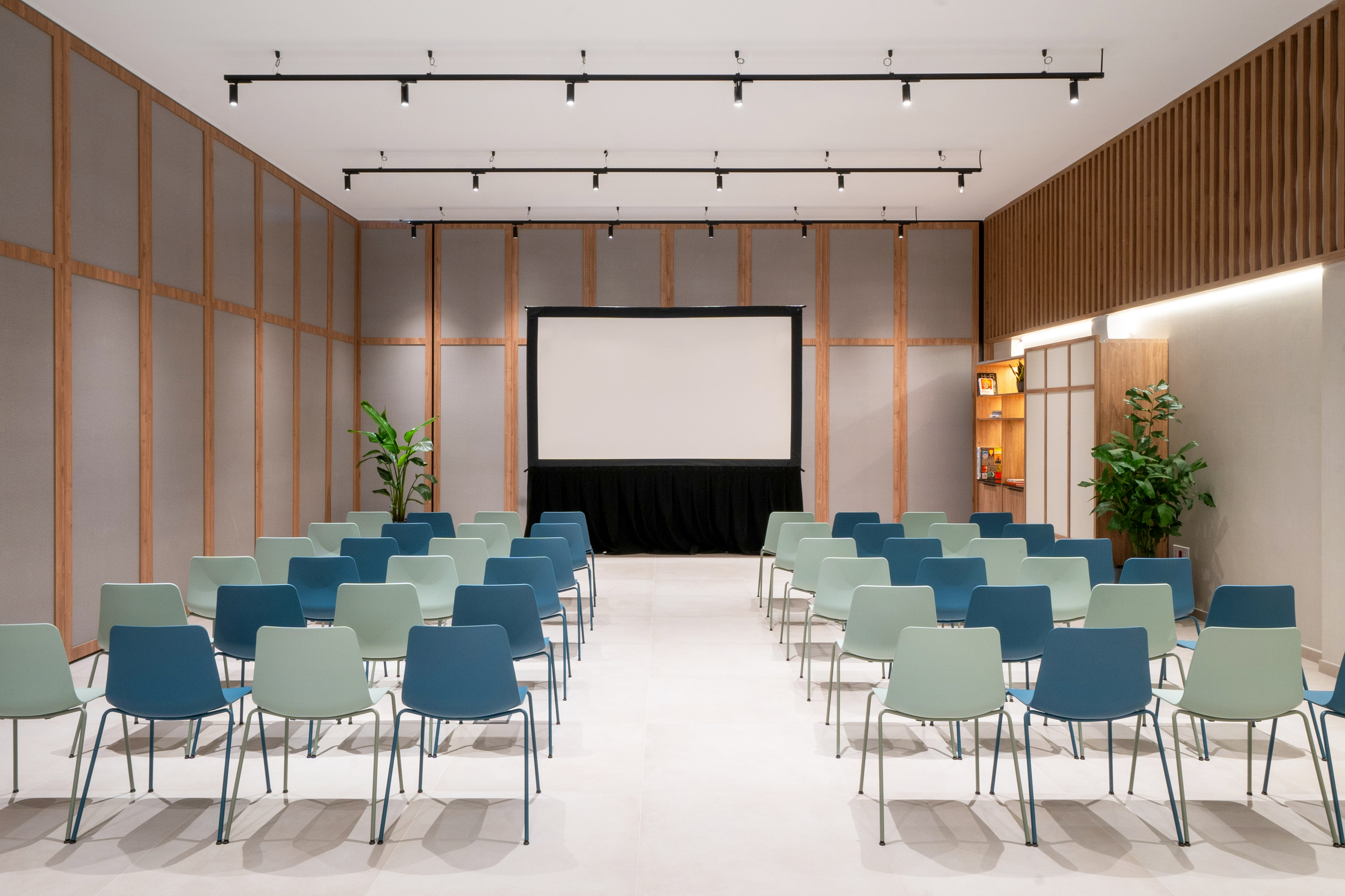 Modern conference room with projection screen and blue, green chairs.