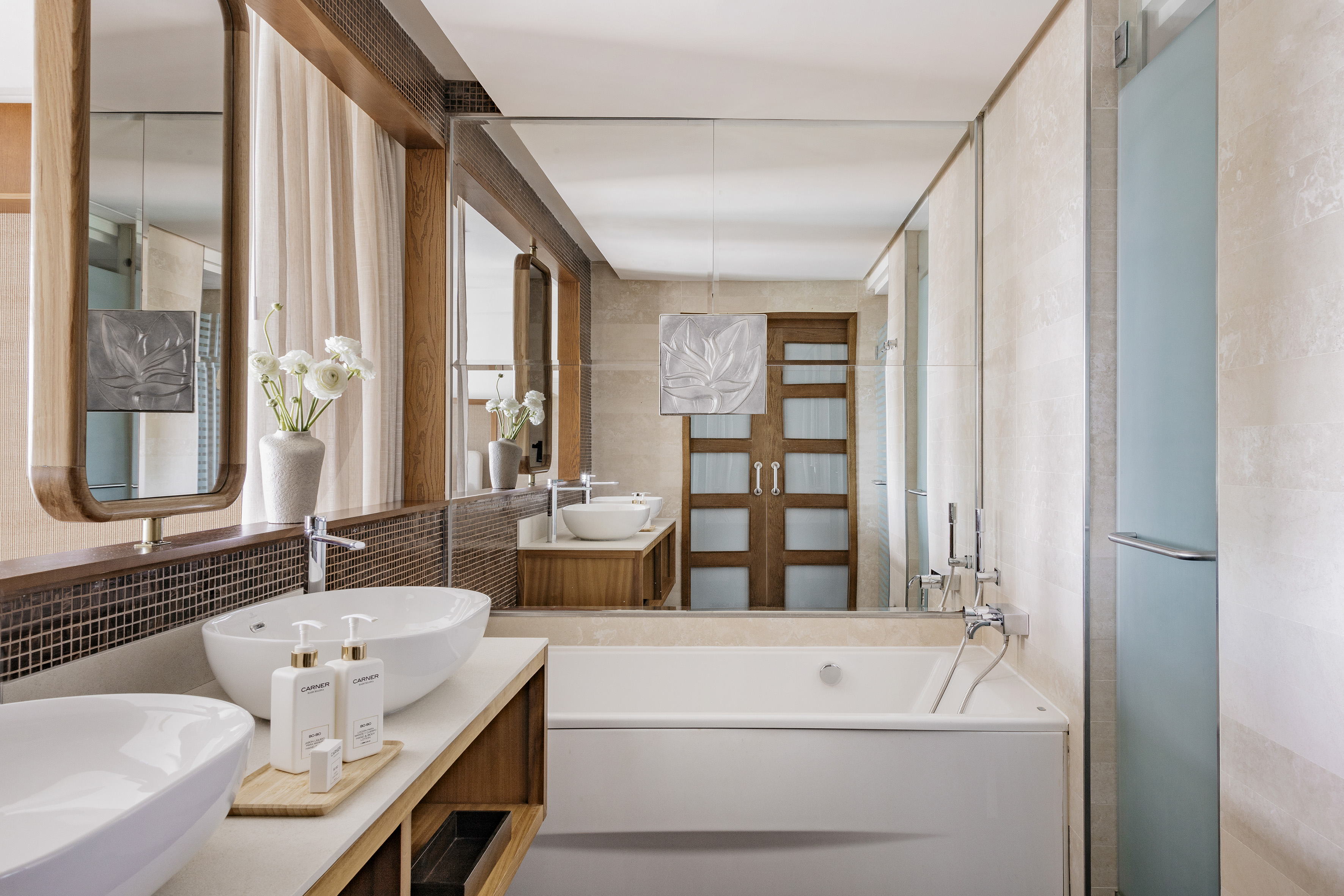 Stylish modern bathroom with double sinks, large mirror, and elegant bathtub.
