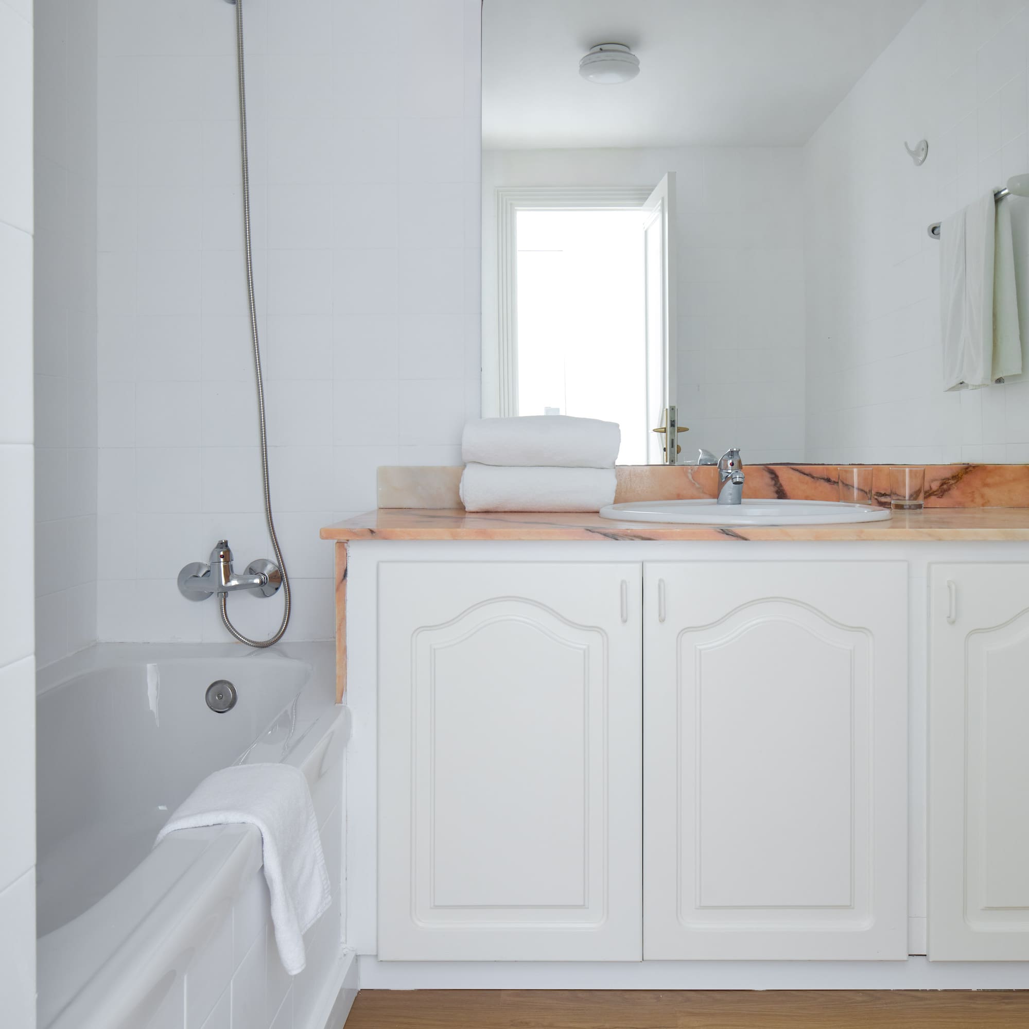 a bathroom with white cabinets and a bathtub