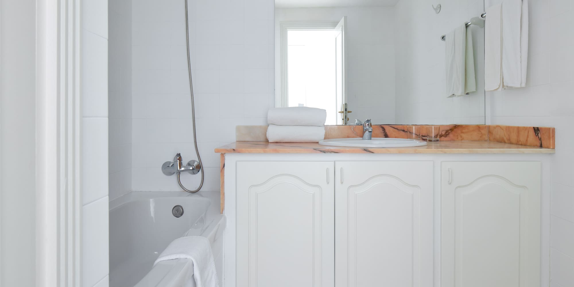 a bathroom with white cabinets and a bathtub