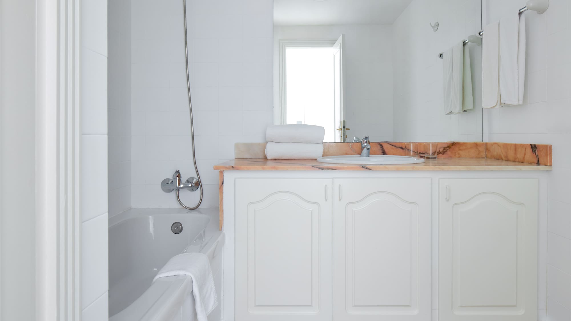 a bathroom with white cabinets and a bathtub