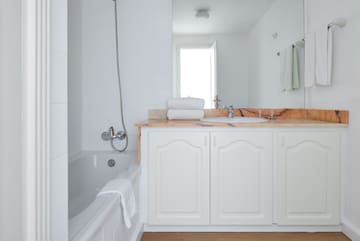 a bathroom with white cabinets and a bathtub