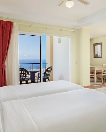a room with two beds and a balcony overlooking the ocean