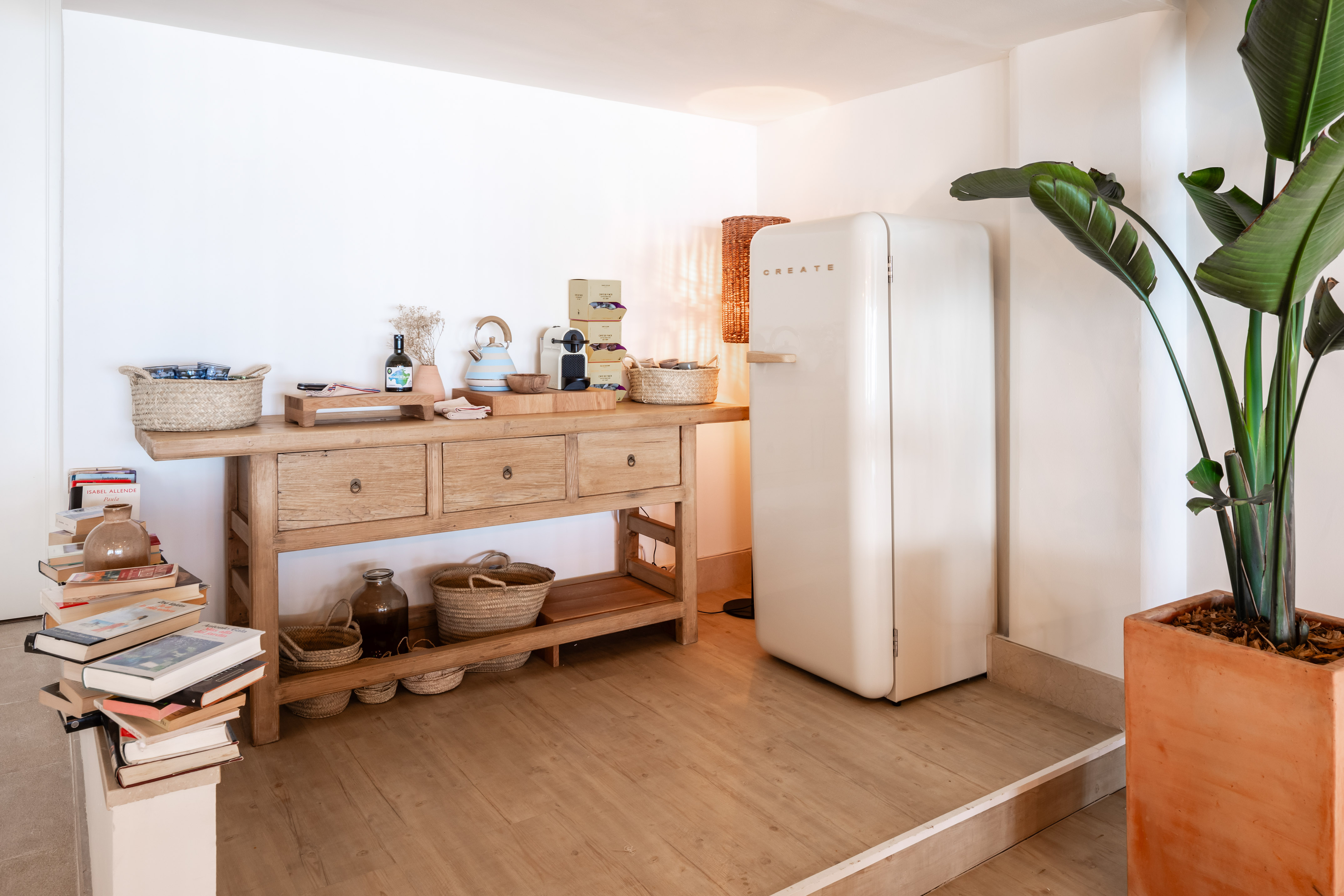 Minimalist kitchen with rustic wooden console, vintage cream fridge, and plant.