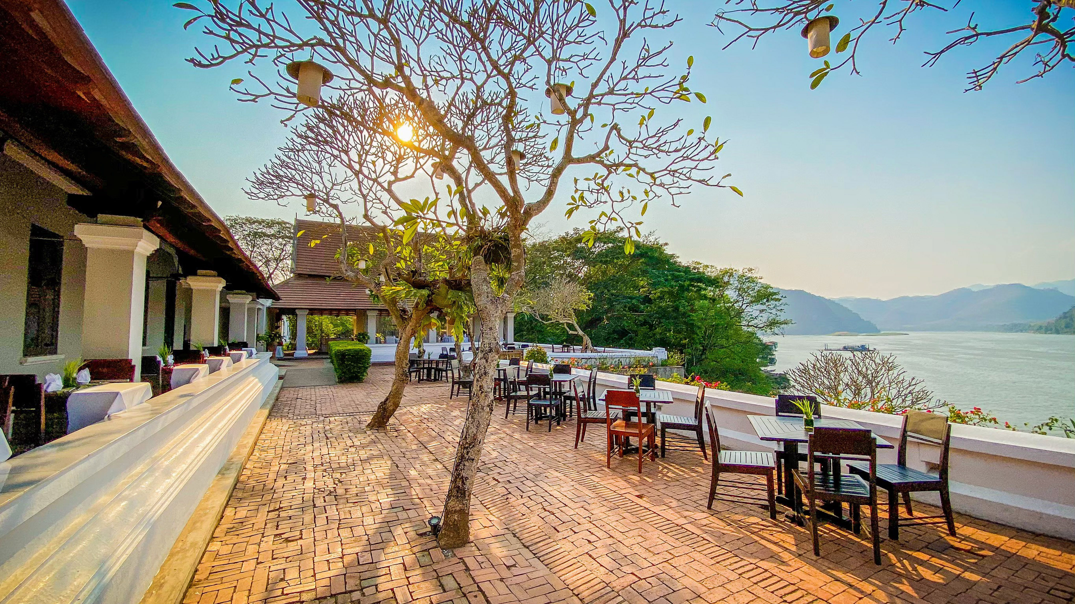 Scenic outdoor restaurant terrace with river, mountain views and sunset glow.