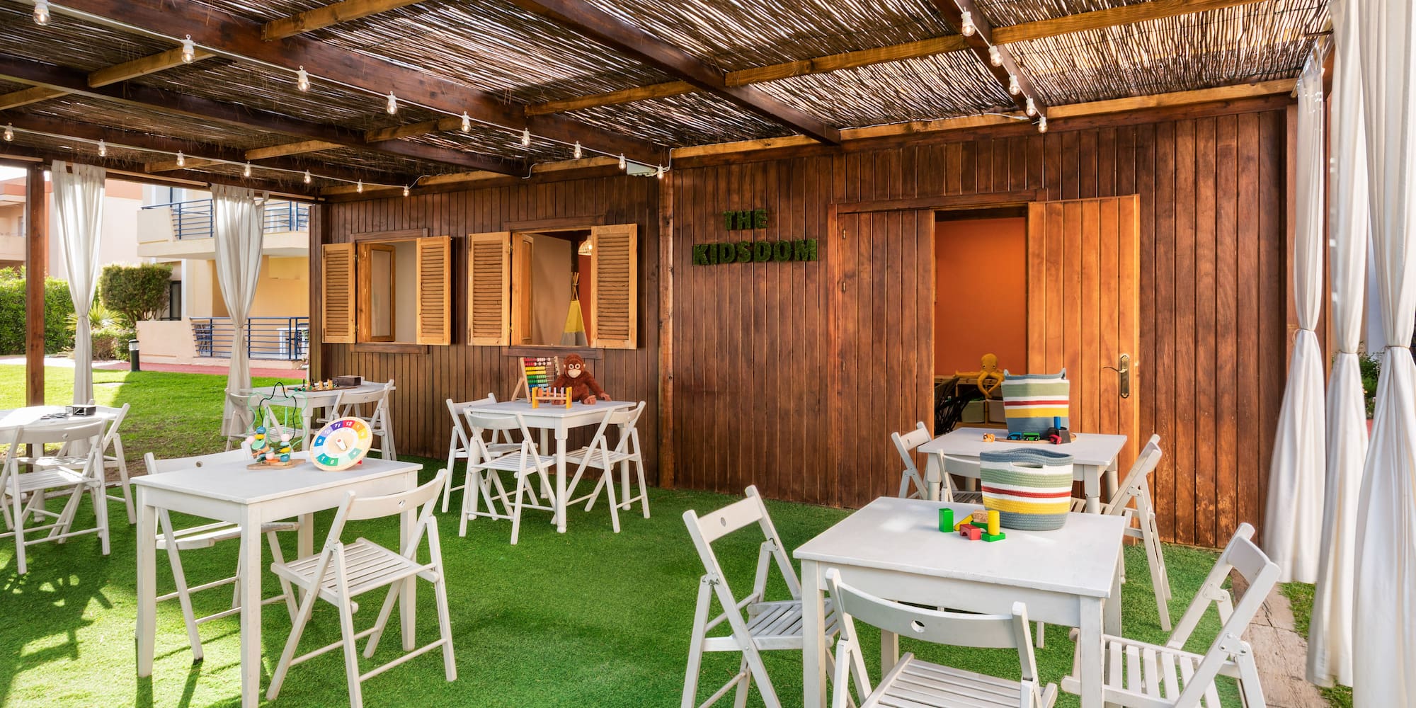 a covered patio with white tables and chairs