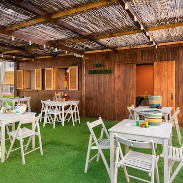 a covered patio with white tables and chairs