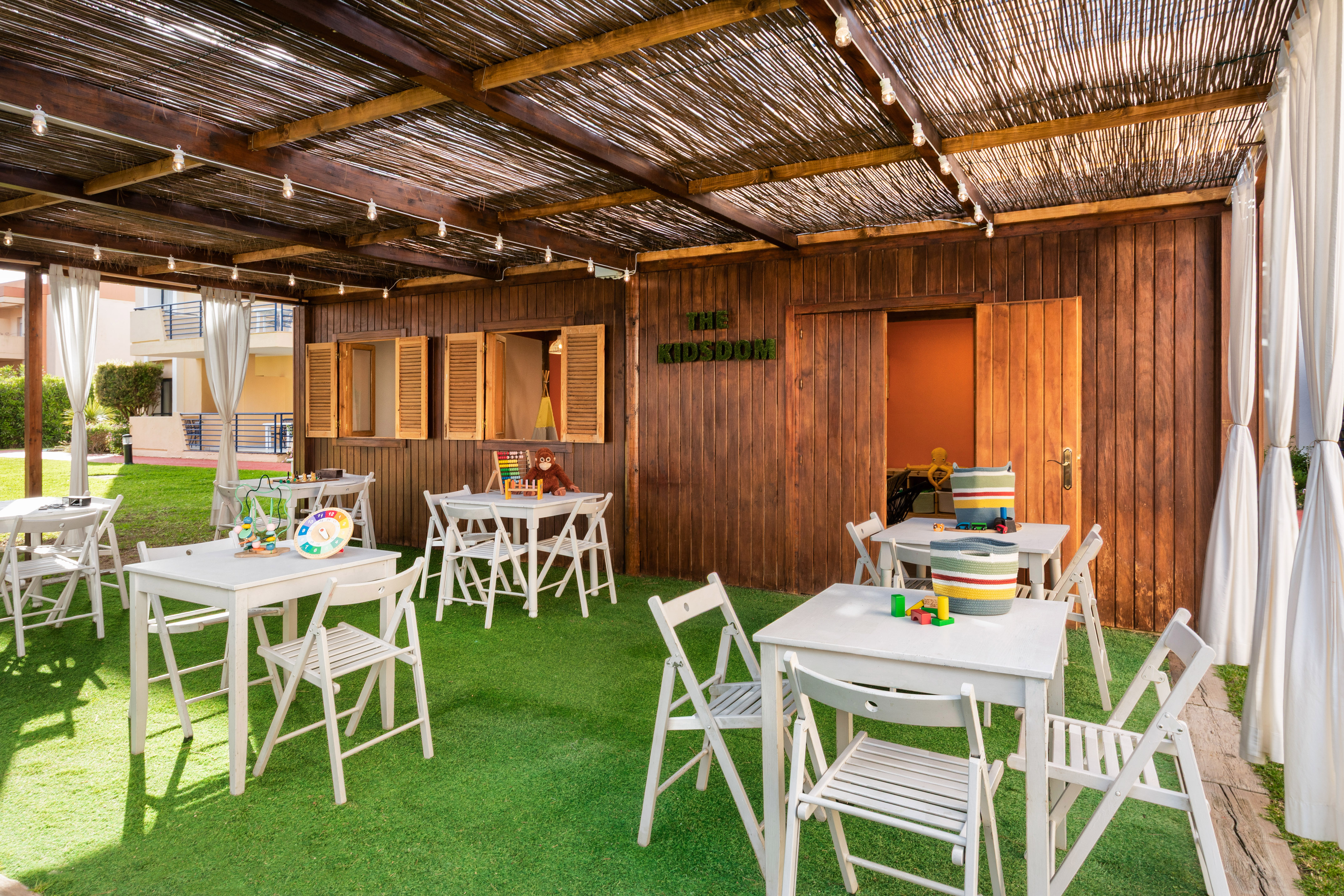 a covered patio with white tables and chairs