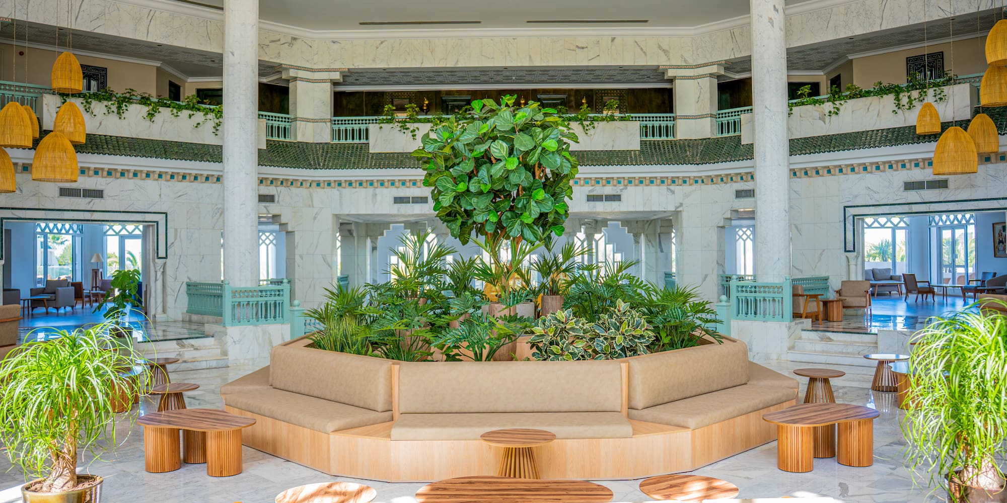 Resort lobby with central plant display, circular lounge seating, and marble.
