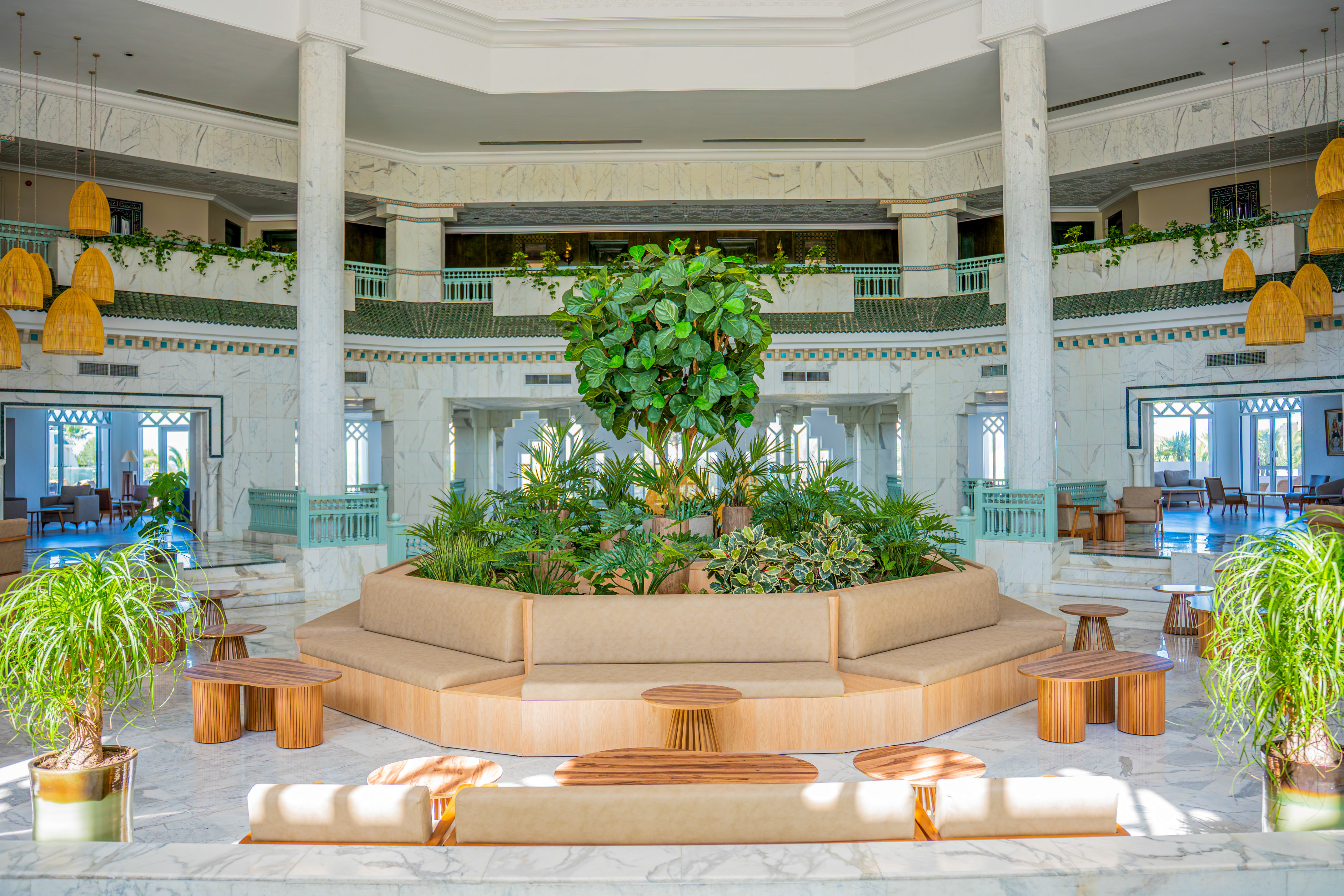 Resort lobby atrium with central plants, modern lounge seating, and marble design.