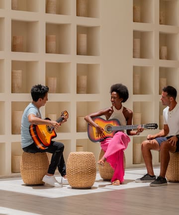 a group of people sitting on stools playing guitars