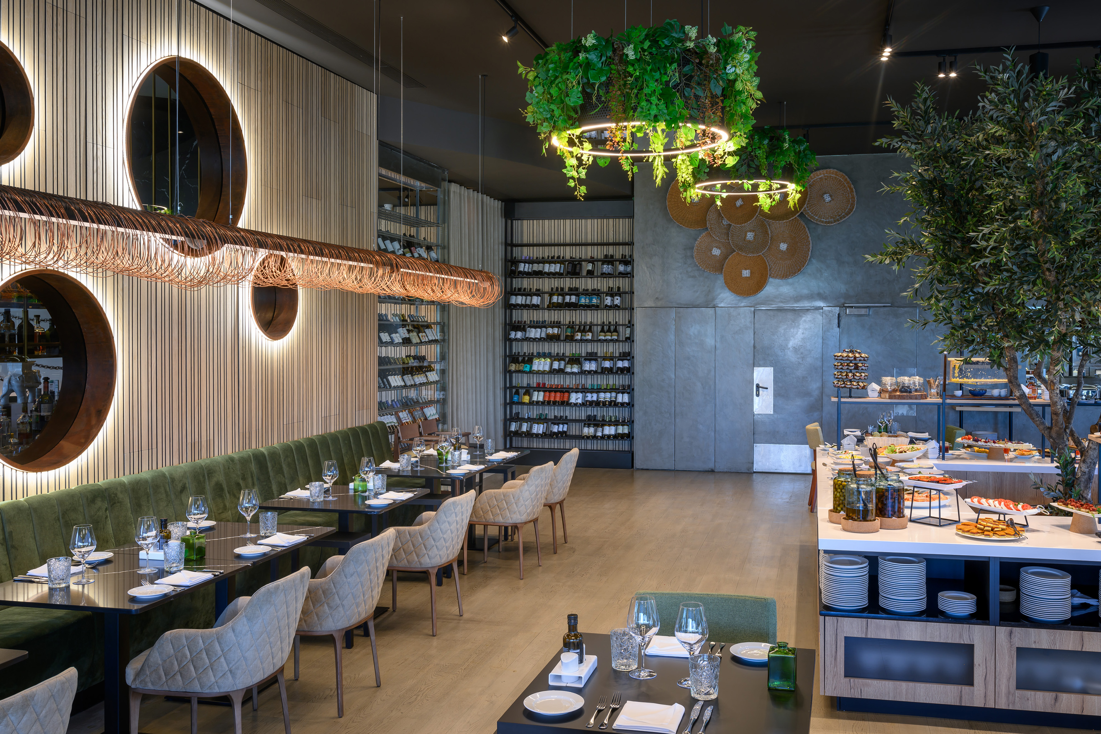 Modern restaurant interior, green banquettes, elegant tables, wine display, buffet.