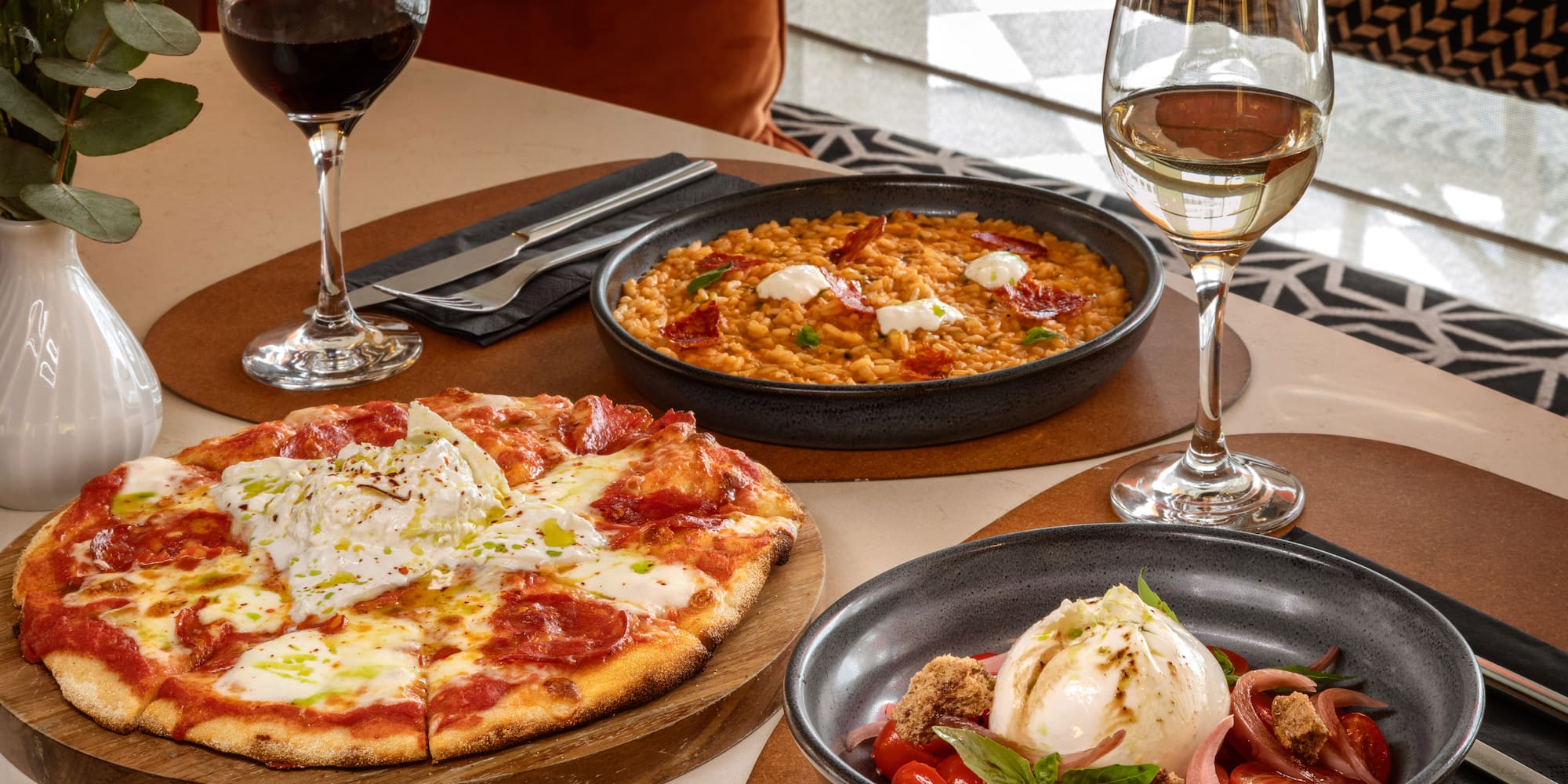 Italian meal: pizza, creamy risotto, burrata salad, red and white wine.