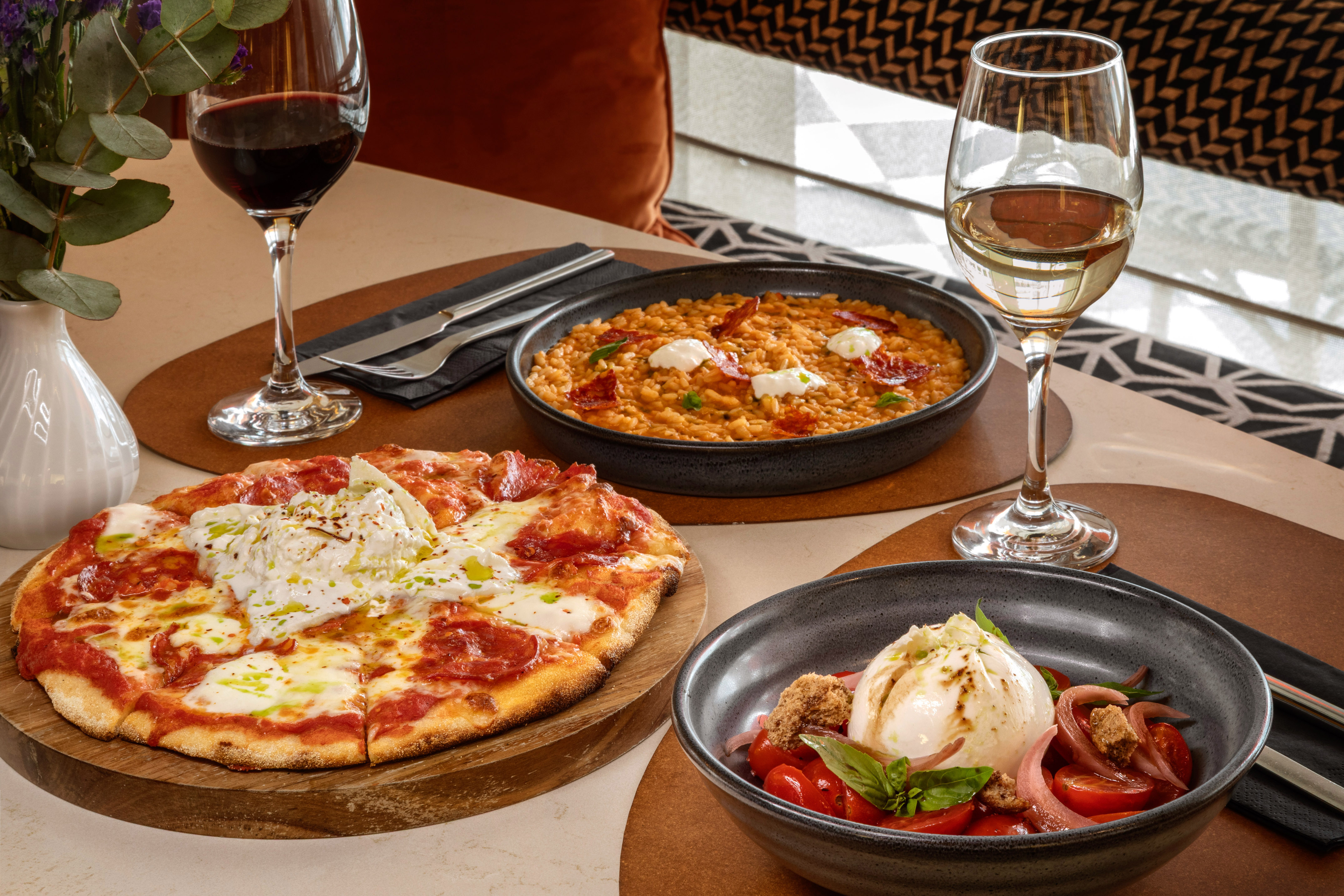 Italian meal: pizza, creamy risotto, burrata salad, red and white wine.