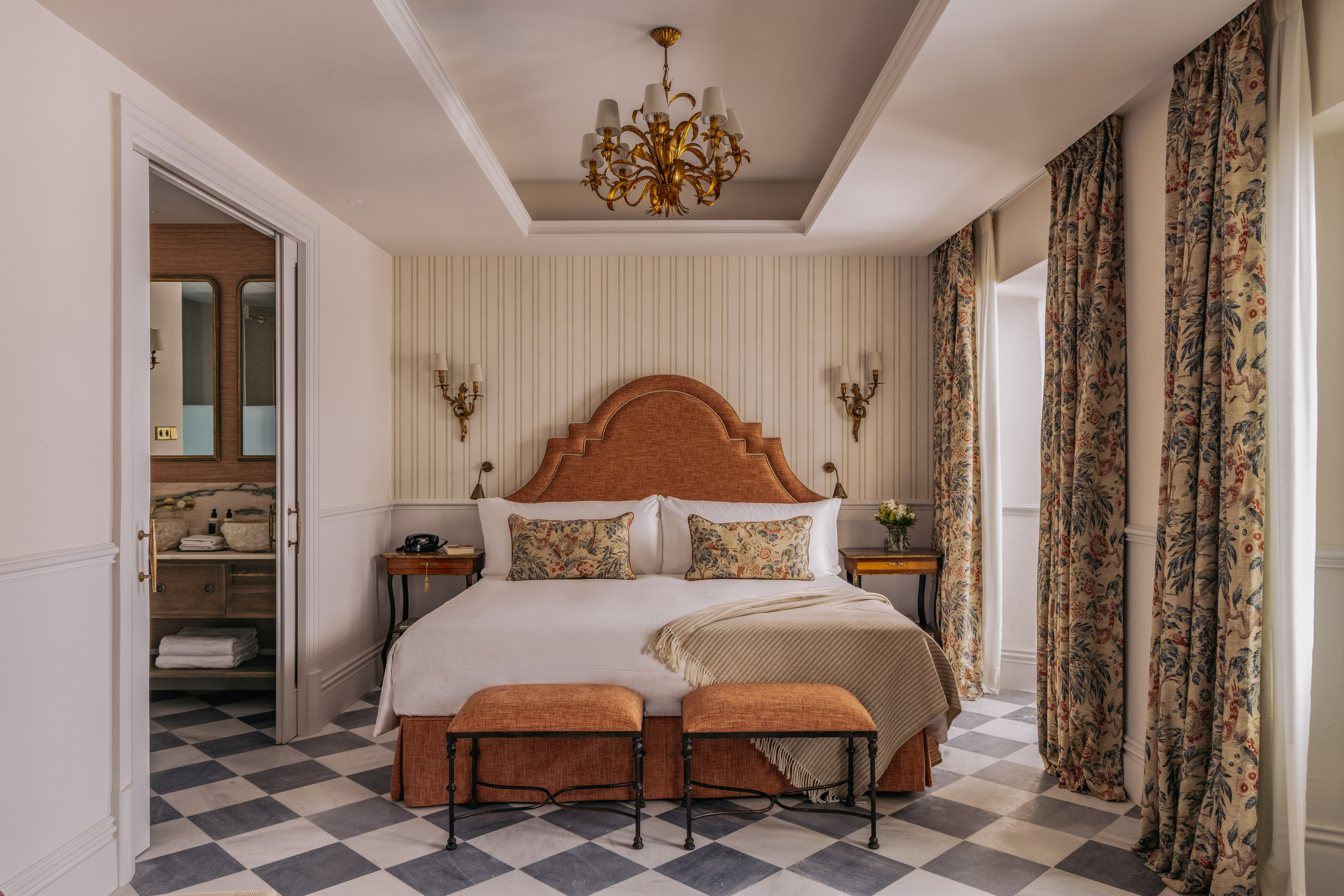 Luxurious bedroom suite with orange headboard, checkered floor, and floral curtains.
