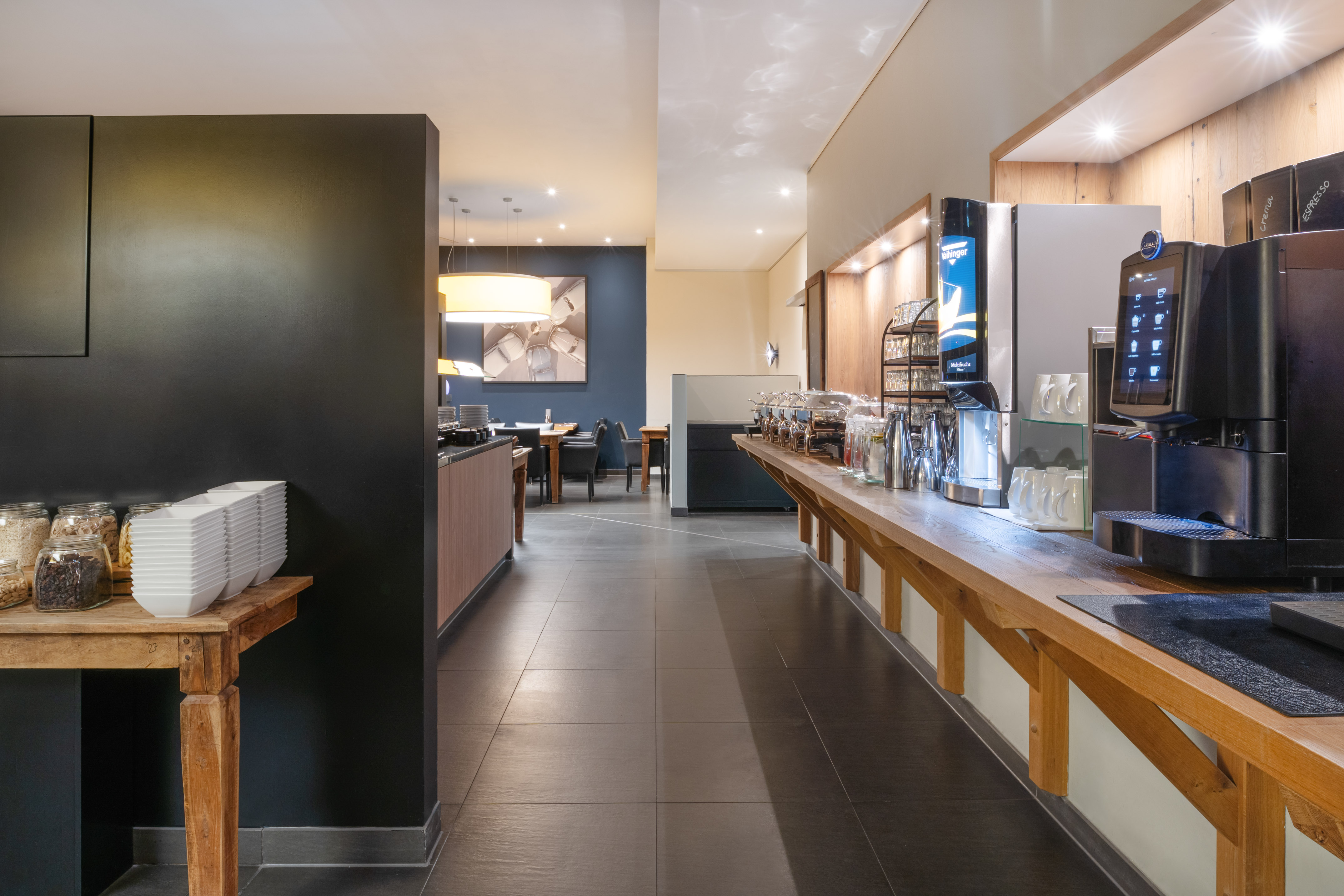 Spacious hotel breakfast buffet with coffee, cereal station, and dining room.