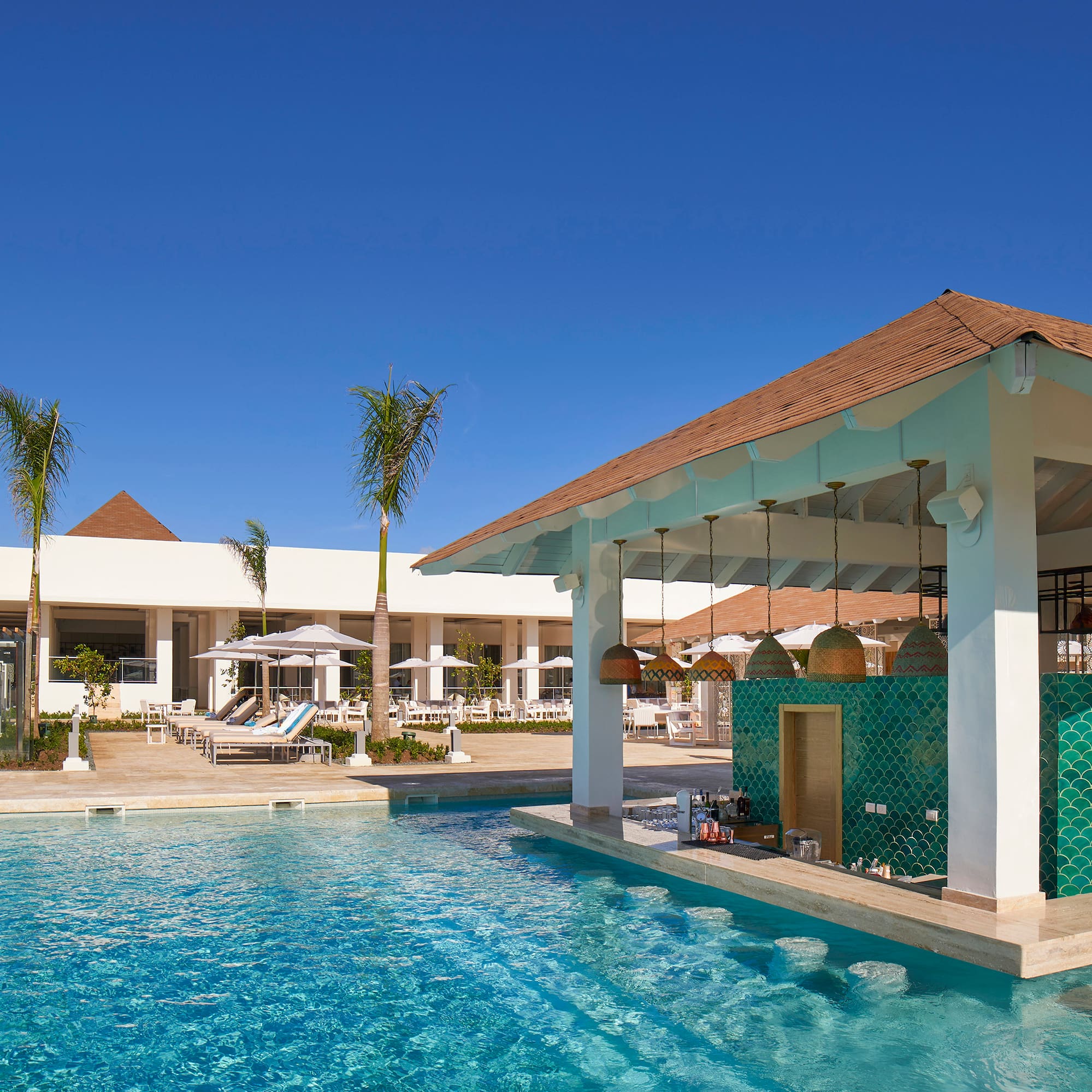 Luxury resort pool with swim-up bar, green tiles, and palm trees.