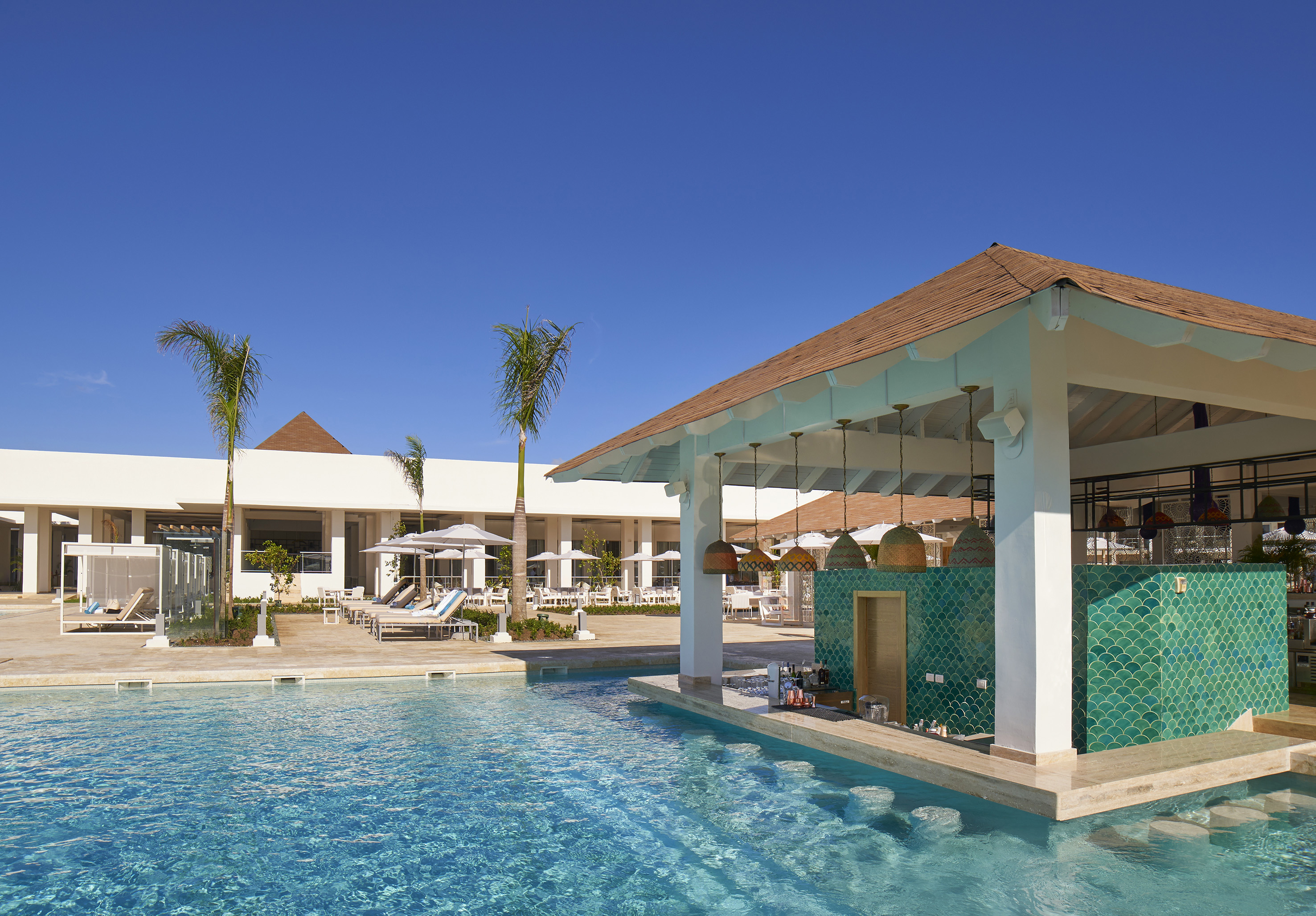 Luxury resort pool with swim-up bar, green tiles, and palm trees.