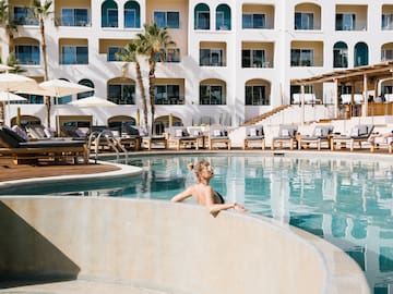 a woman in a pool with a white building behind her