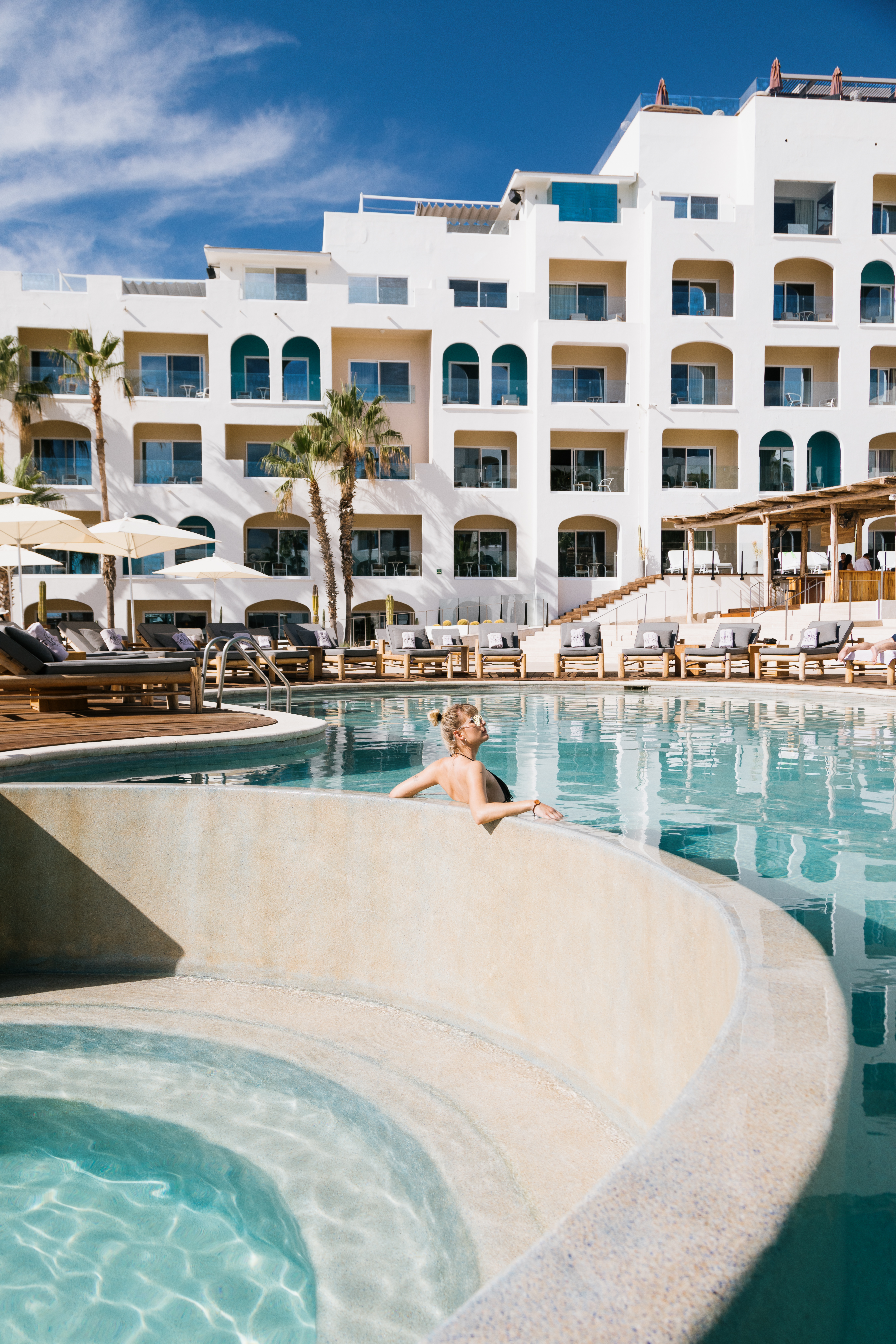 a woman in a pool with a white building behind her