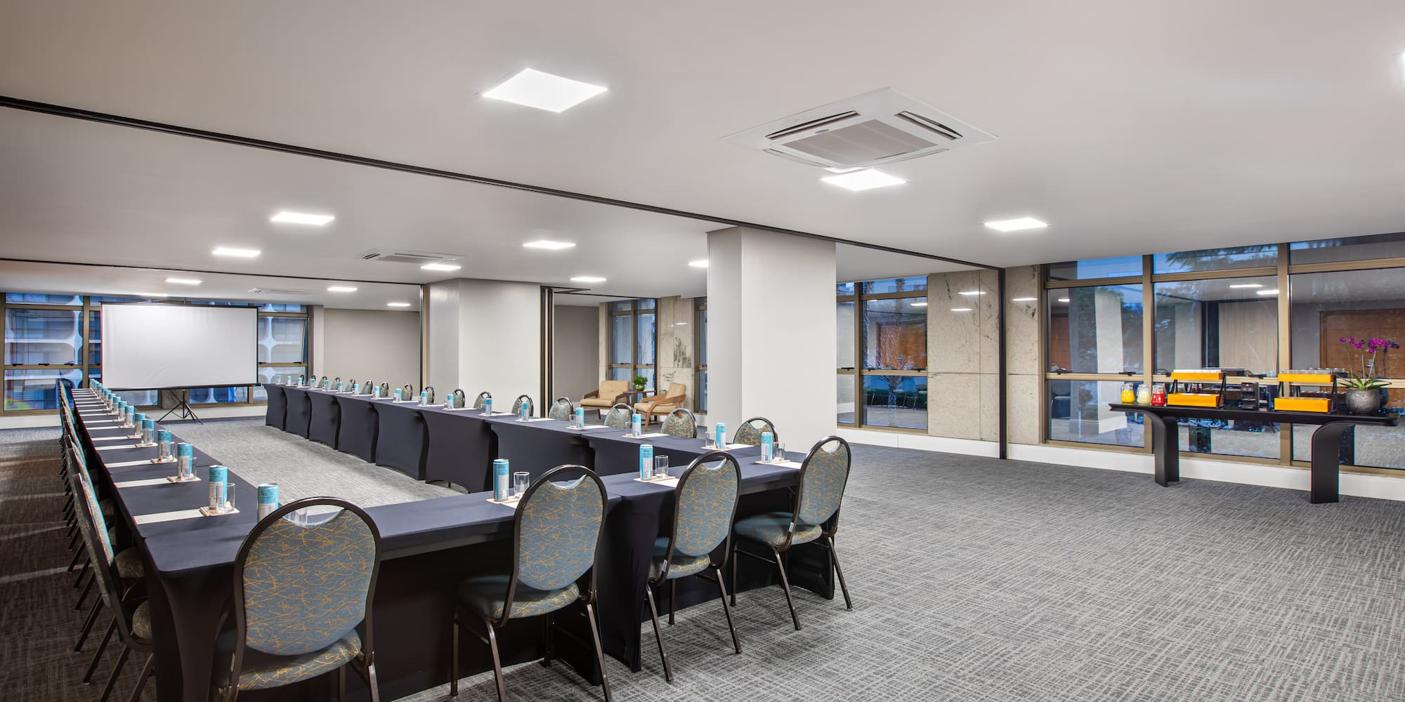 Empty U-shaped conference room with presentation screen and buffet station.