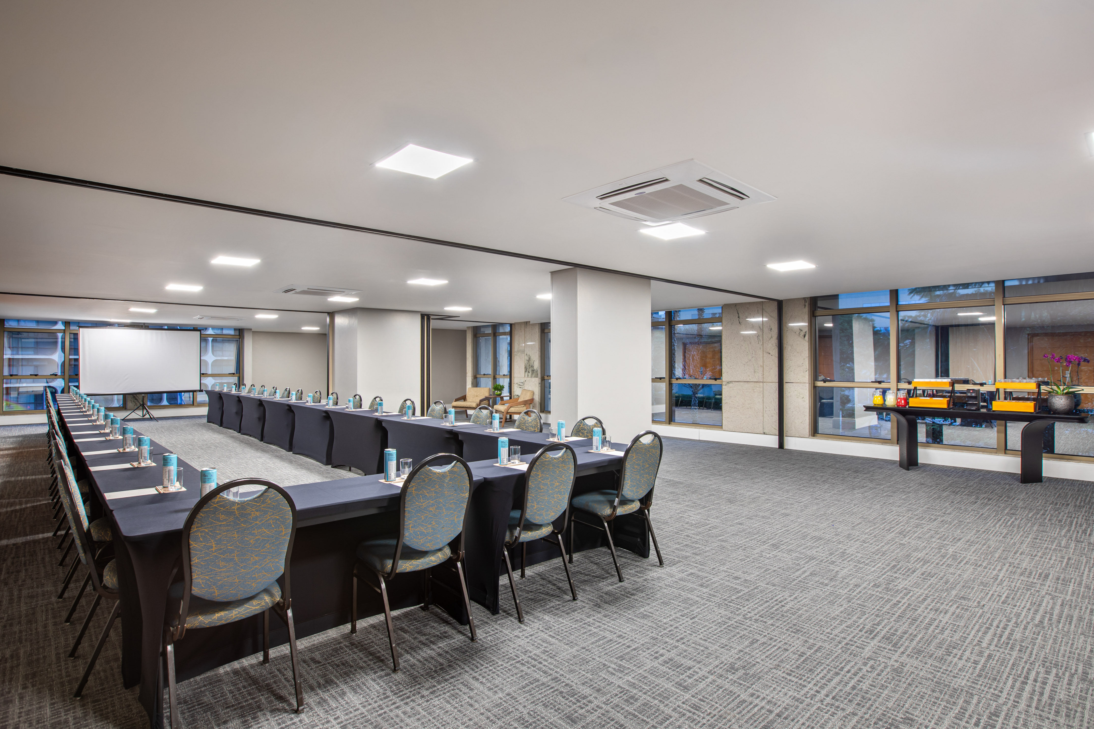 Empty U-shaped conference room with presentation screen and buffet station.