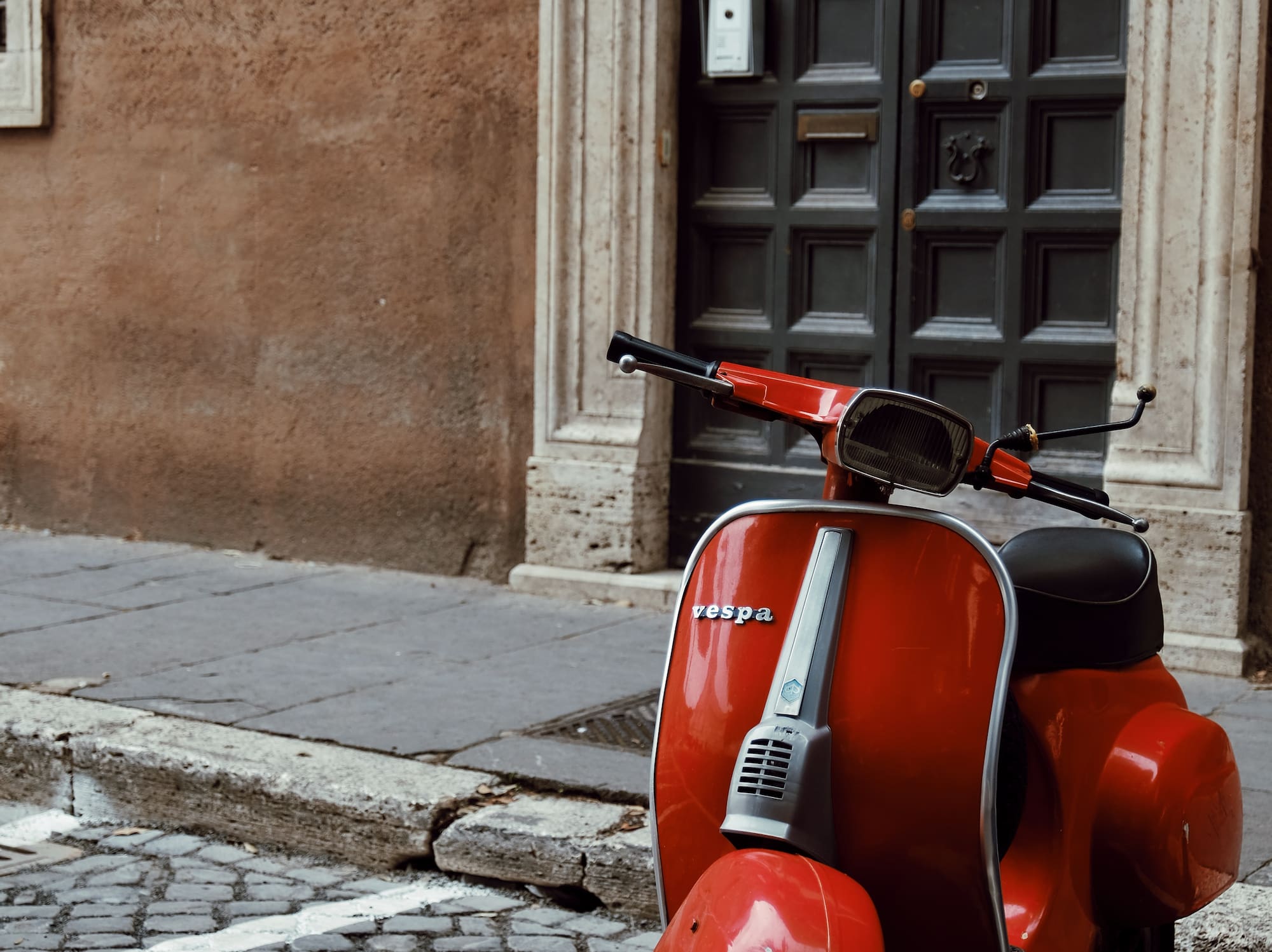 a red scooter parked on a brick sidewalk