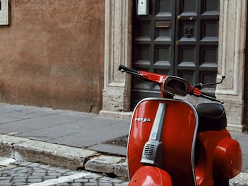 a red scooter parked on a brick sidewalk