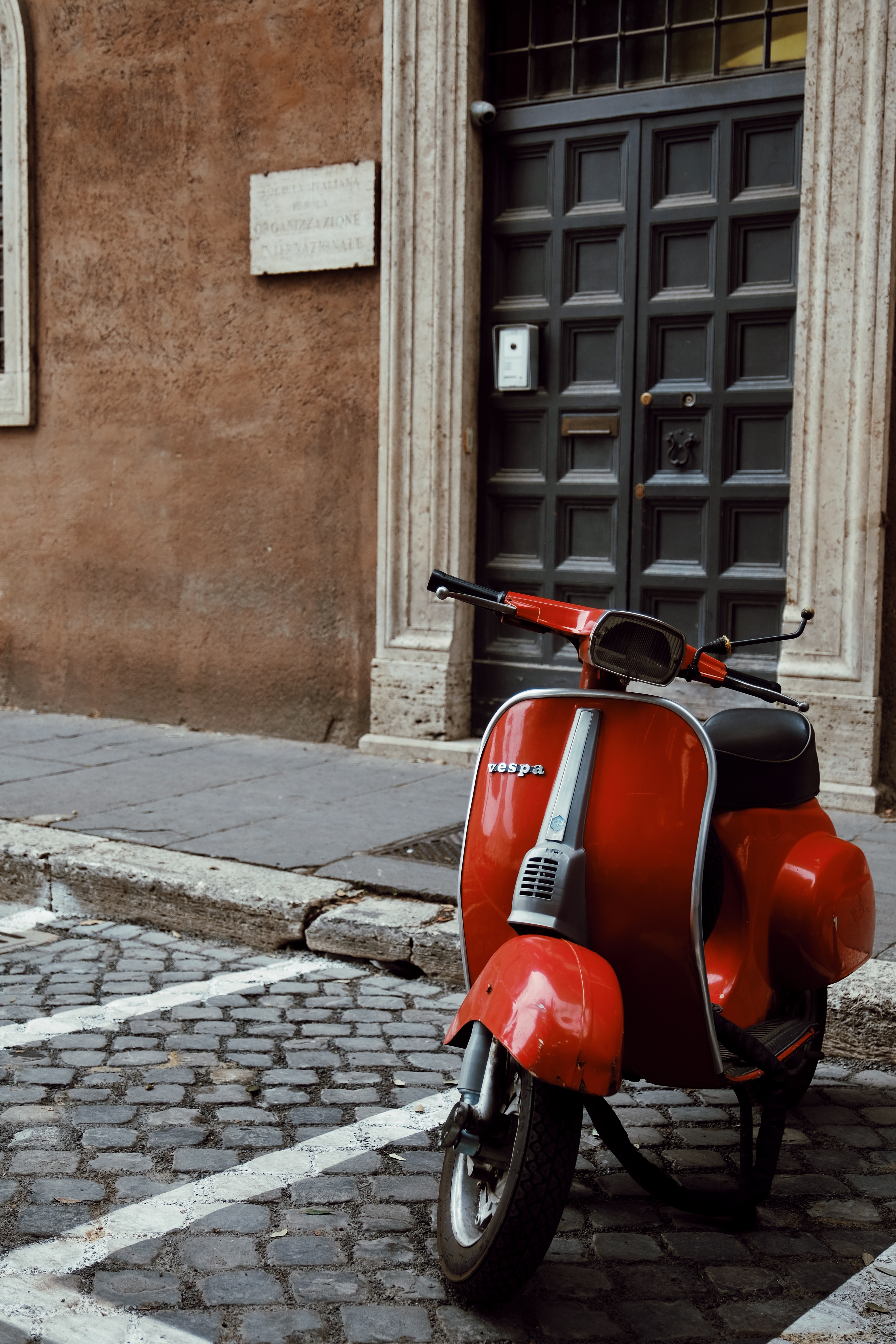 a red scooter parked on a brick sidewalk