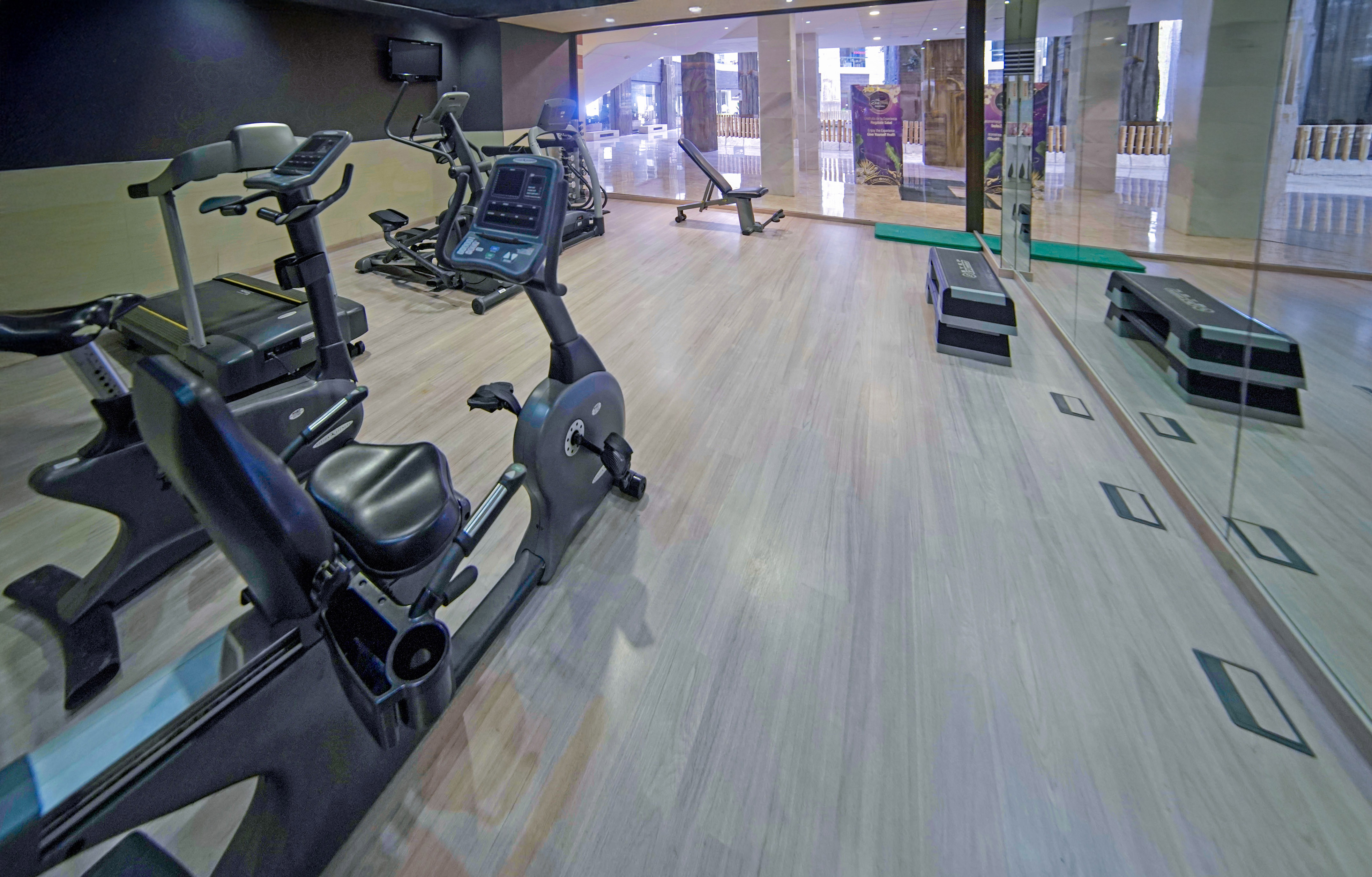 Modern gym with recumbent bike, treadmill, elliptical, weight bench, and mirrors.
