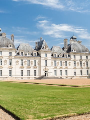 a large white building with a lawn with Château de Cheverny in the background