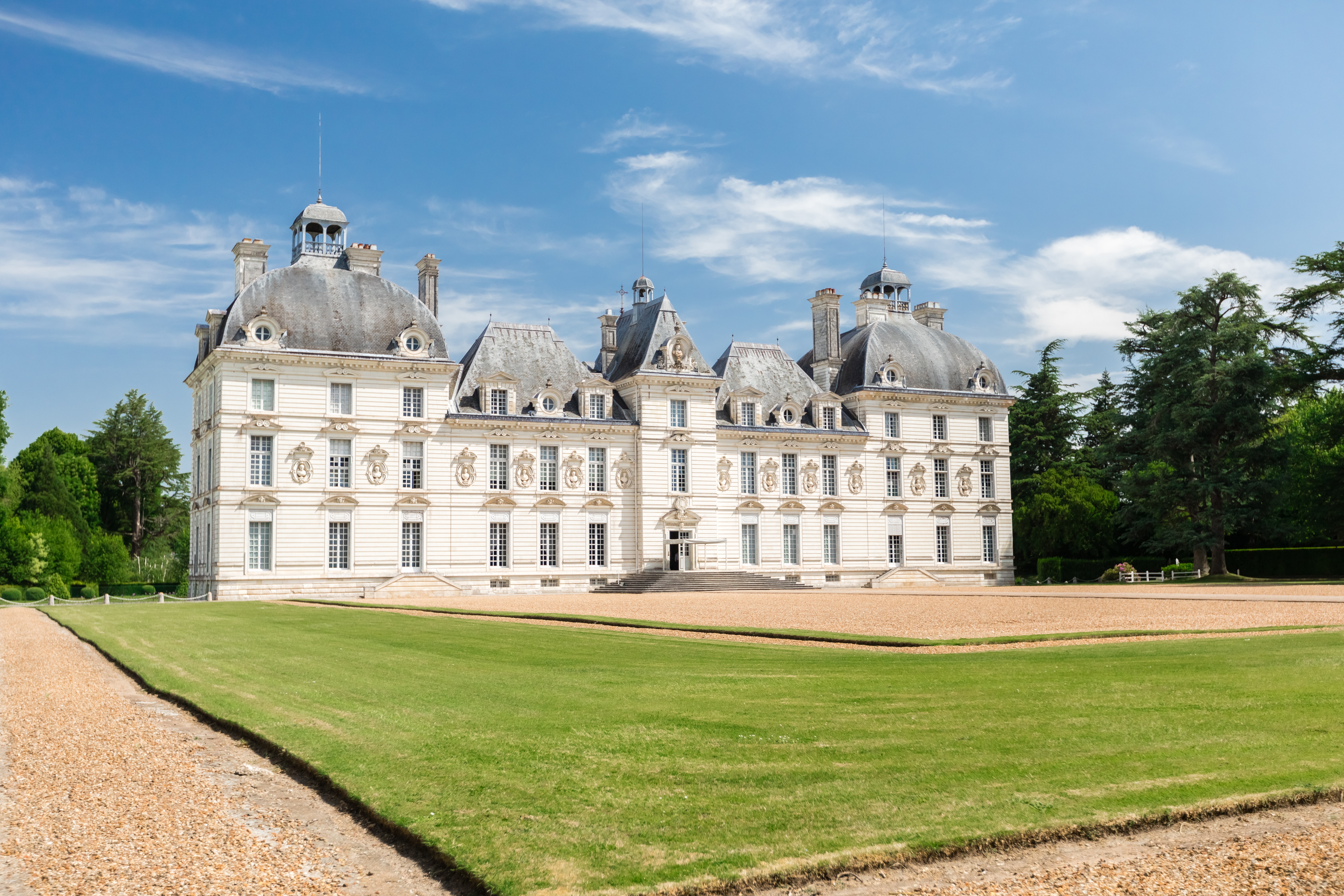 a large white building with a lawn with Château de Cheverny in the background
