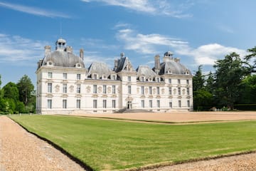 a large white building with a lawn with Château de Cheverny in the background